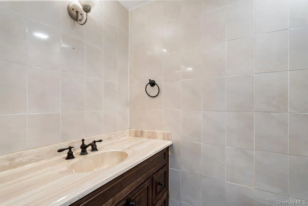 Bathroom vanity featuring a light-toned stone countertop with an integrated oval sink and bronze-finish fixtures Bathroom vanity featuring a light-toned stone countertop with an integrated oval sink and bronze-finish fixtures