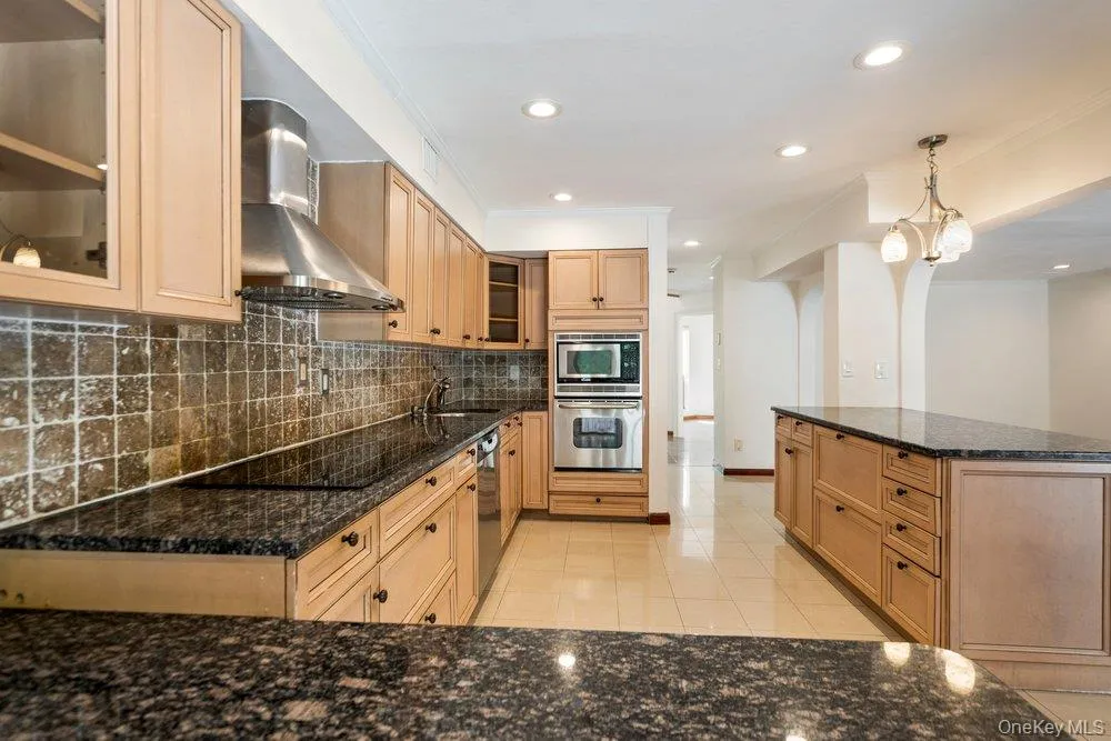 Kitchen featuring light wood-finish cabinetry, dark speckled countertops, and an integrated wall oven with a microwave Kitchen featuring light wood-finish cabinetry, dark speckled countertops, and an integrated wall oven with a microwave