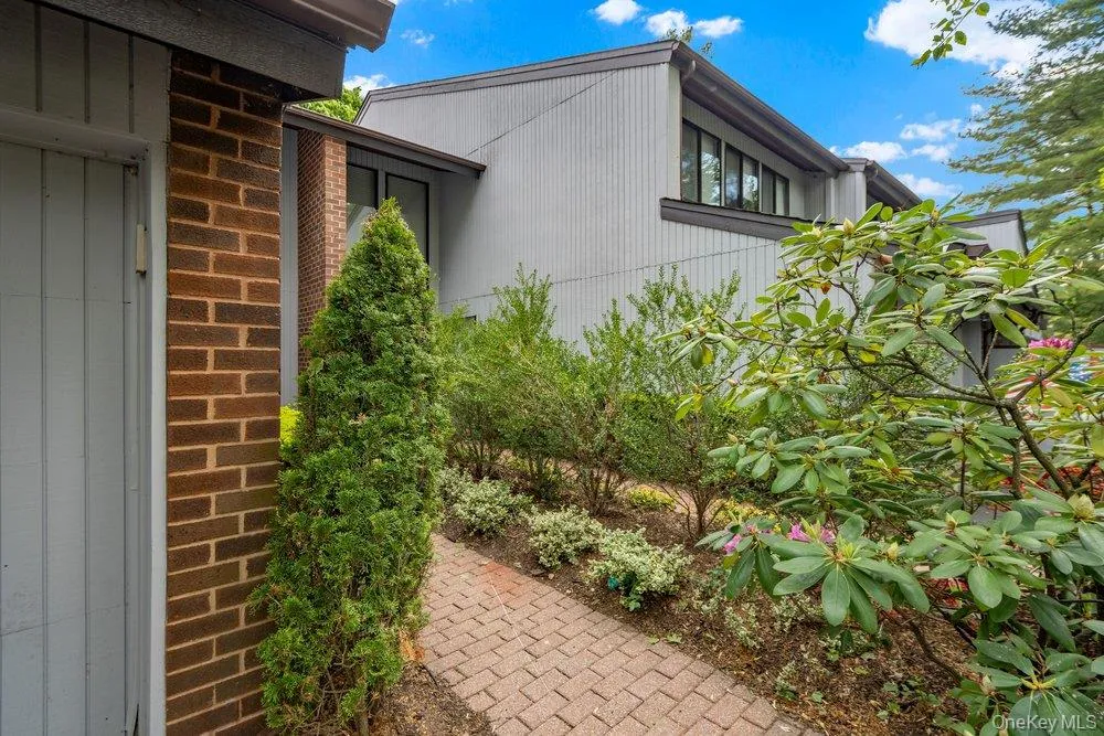 Modern exterior featuring multi-paned windows, a brick accent wall, and a herringbone-patterned paver walkway Modern exterior featuring multi-paned windows, a brick accent wall, and a herringbone-patterned paver walkway