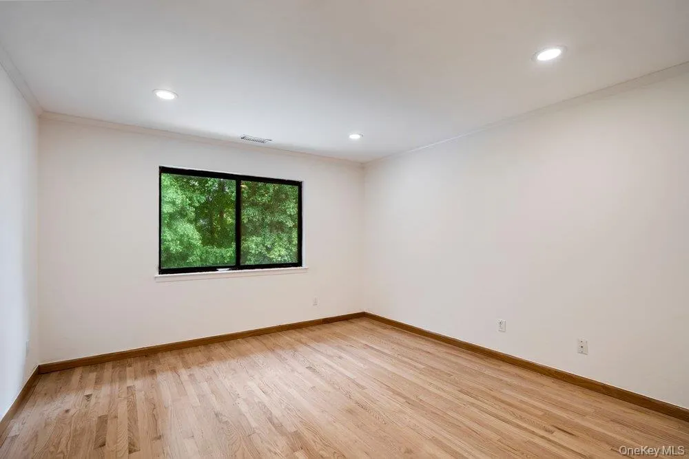 Room featuring a window with black trim, wood-finish flooring, recessed lighting, and crown molding Room featuring a window with black trim, wood-finish flooring, recessed lighting, and crown molding