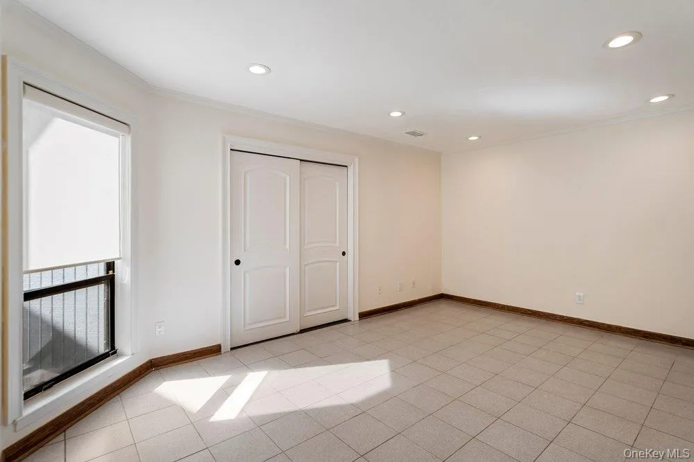 Room with light tile flooring, recessed lighting, and a window featuring a roller shade Room with light tile flooring, recessed lighting, and a window featuring a roller shade