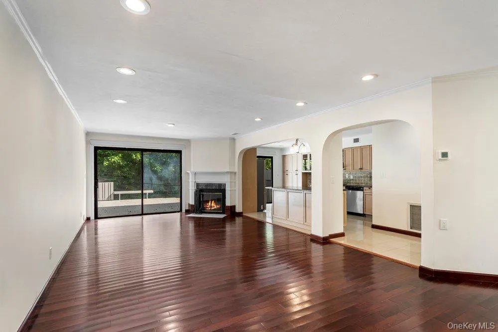 Spacious living area featuring rich wood-finish flooring, recessed lighting, and a stone-surround fireplace Spacious living area featuring rich wood-finish flooring, recessed lighting, and a stone-surround fireplace