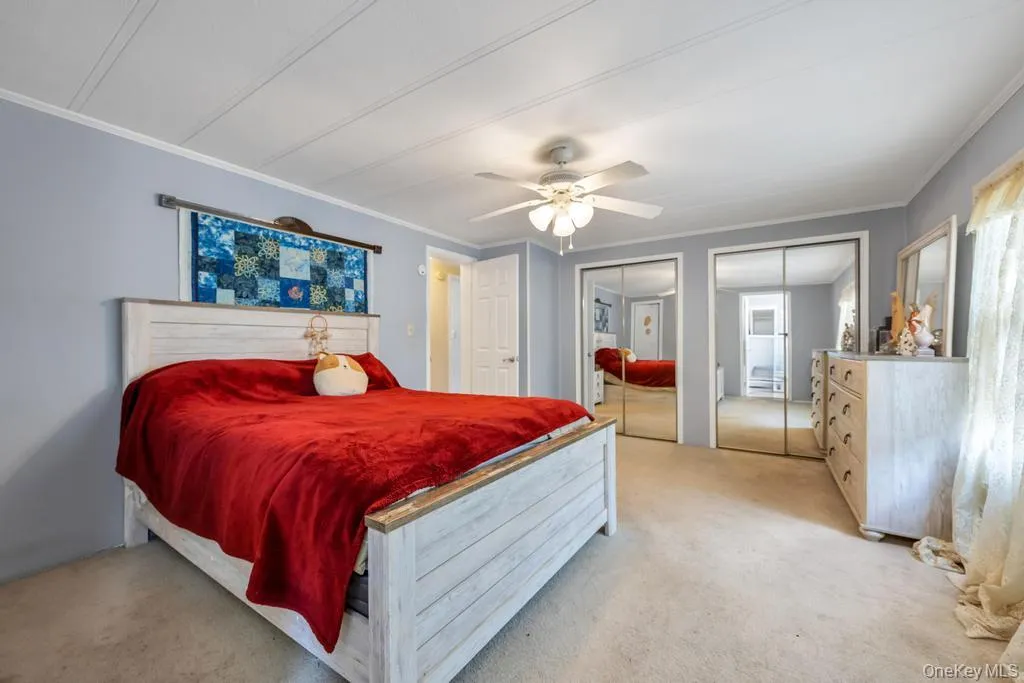 Bedroom featuring light blue walls, a white ceiling fan, and carpeted flooring Bedroom featuring light blue walls, a white ceiling fan, and carpeted flooring