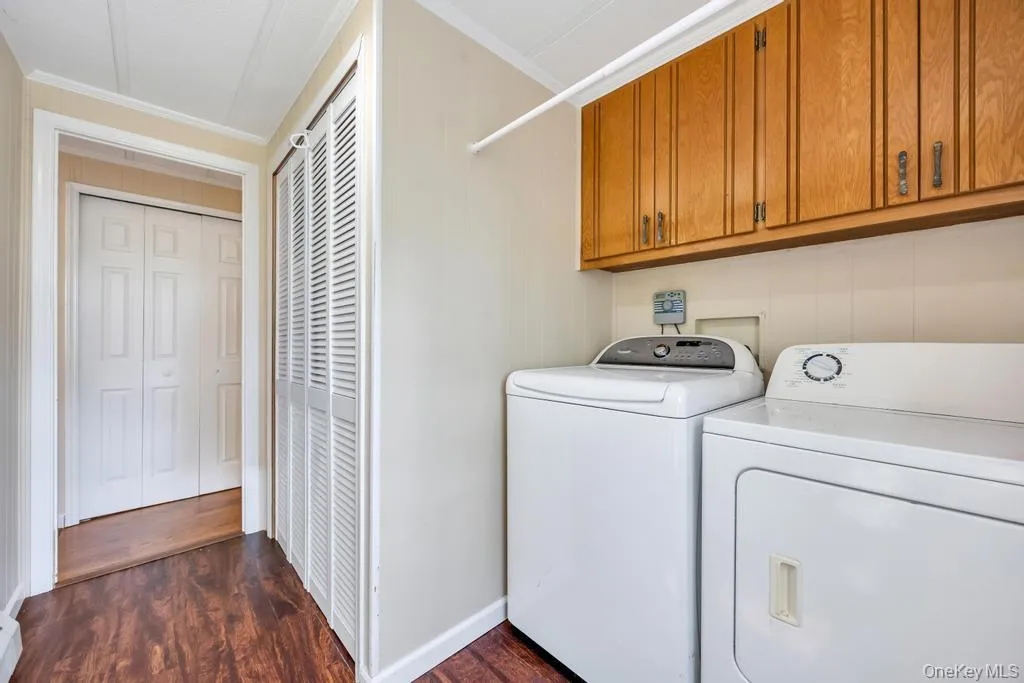 Dedicated laundry area featuring wood-finish flooring, overhead wood cabinetry, and beadboard wainscoting Dedicated laundry area featuring wood-finish flooring, overhead wood cabinetry, and beadboard wainscoting