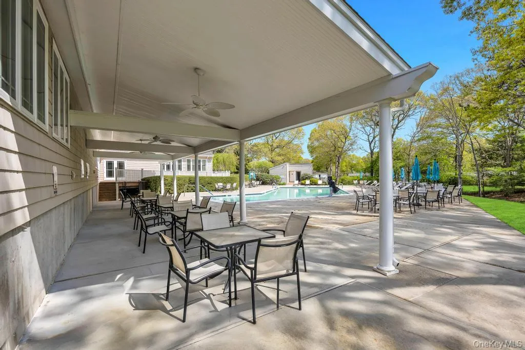 Covered patio space featuring multiple tables and chairs, two ceiling fans, and a concrete surface Covered patio space featuring multiple tables and chairs, two ceiling fans, and a concrete surface