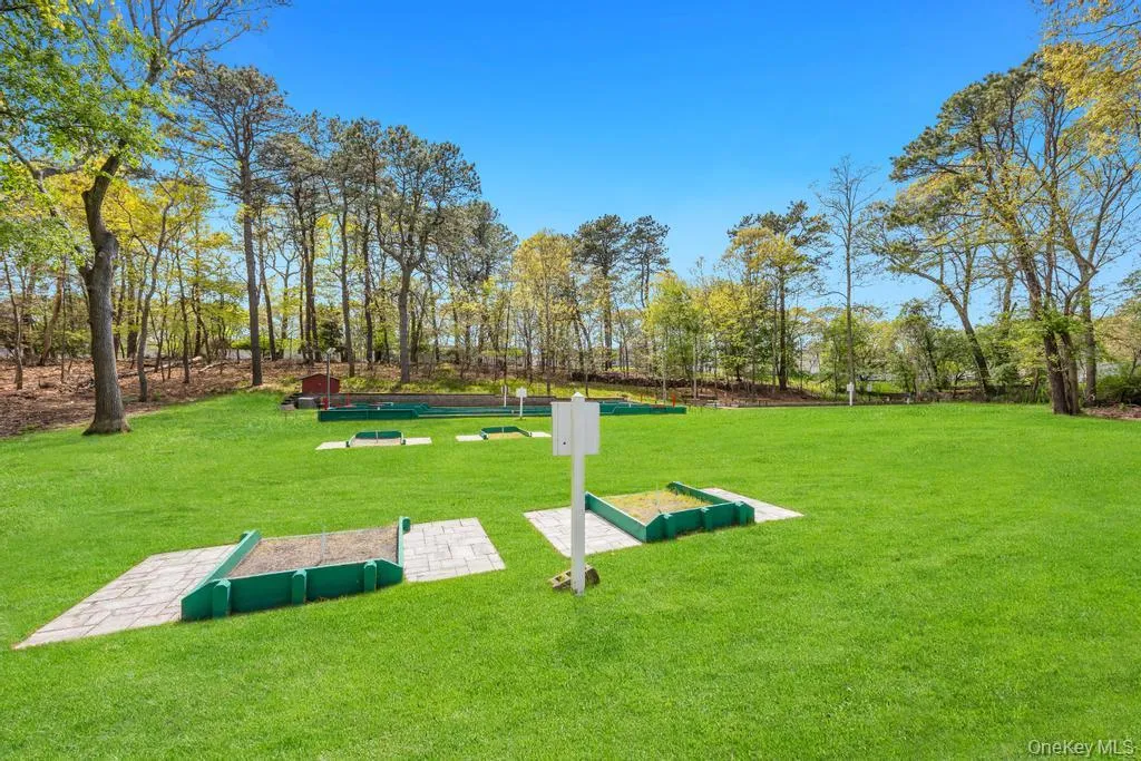 Expansive lawn featuring a miniature golf course with multiple holes, paver stone pathways, and mature tree landscaping Expansive lawn featuring a miniature golf course with multiple holes, paver stone pathways, and mature tree landscaping