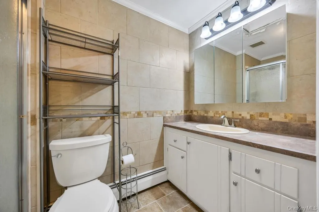 Bathroom featuring a single vanity with white cabinetry, an integrated sink, and a laminate countertop Bathroom featuring a single vanity with white cabinetry, an integrated sink, and a laminate countertop