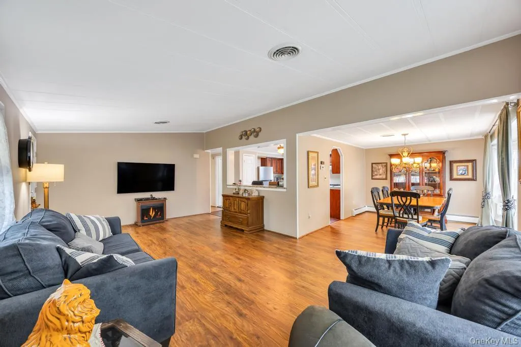 Spacious living area featuring wood-finish flooring and a decorative electric fireplace Spacious living area featuring wood-finish flooring and a decorative electric fireplace