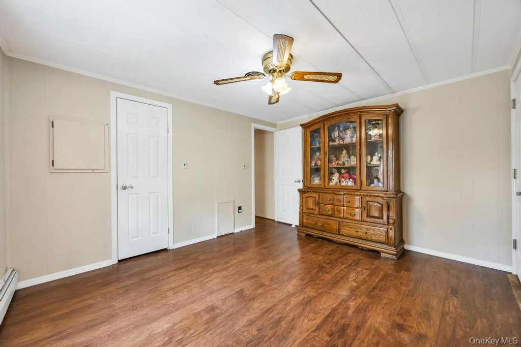 Room featuring wood-finish flooring, neutral wall tones, and white trim Room featuring wood-finish flooring, neutral wall tones, and white trim