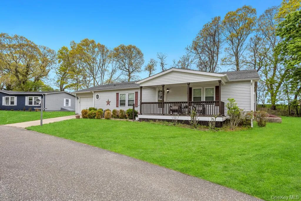Single-story residence featuring white siding, a covered front porch with dark railings, and a side-facing garage Single-story residence featuring white siding, a covered front porch with dark railings, and a side-facing garage