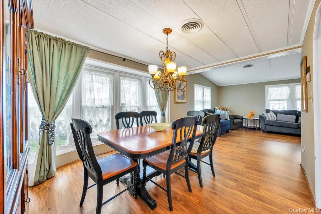 Dining area featuring wood-finish flooring, a decorative chandelier, and extensive natural light from multiple windows Dining area featuring wood-finish flooring, a decorative chandelier, and extensive natural light from multiple windows