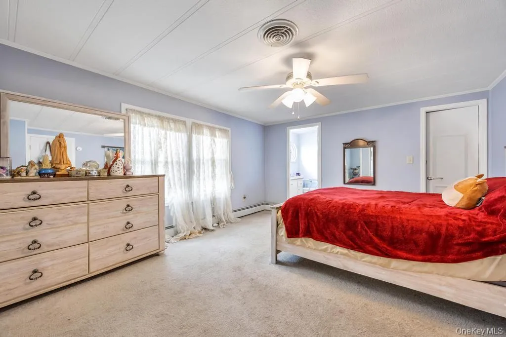 Carpeted room featuring a ceiling fan, two windows with white trim, and white paneled walls with crown molding Carpeted room featuring a ceiling fan, two windows with white trim, and white paneled walls with crown molding