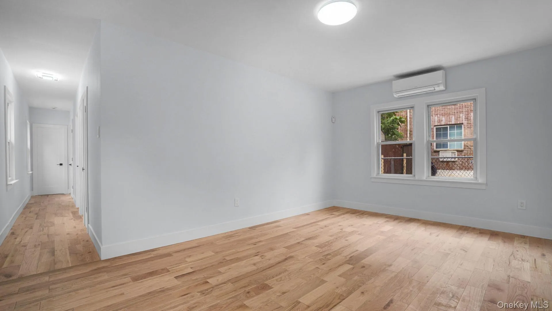Empty room with light wood finished floors and a wall mounted air conditioner Empty room with light wood finished floors and a wall mounted air conditioner