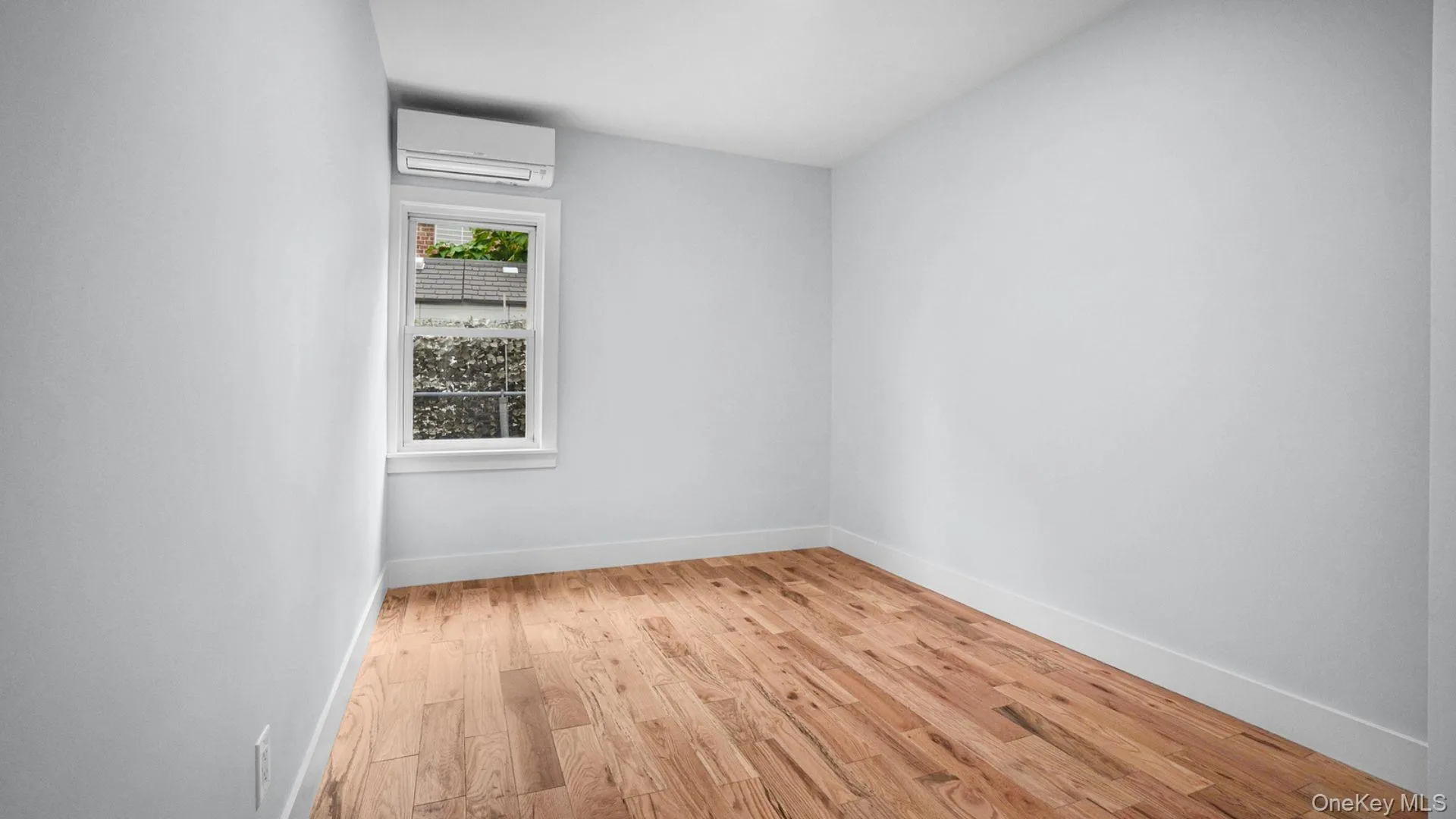 Unfurnished room with light wood-style floors and a wall mounted air conditioner Unfurnished room with light wood-style floors and a wall mounted air conditioner