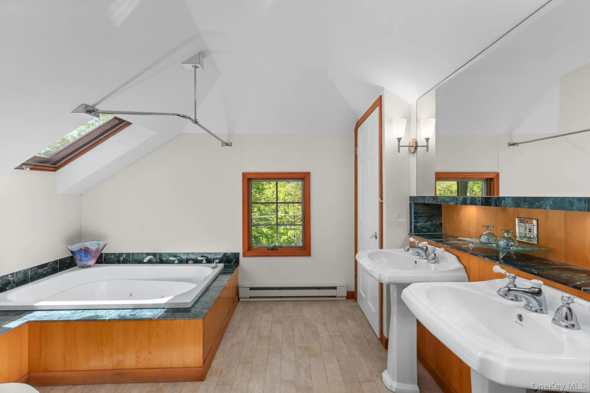 Skylight, large tub, storage and two pedestal sinks add to the bathroom space Skylight, large tub, storage and two pedestal sinks add to the bathroom space