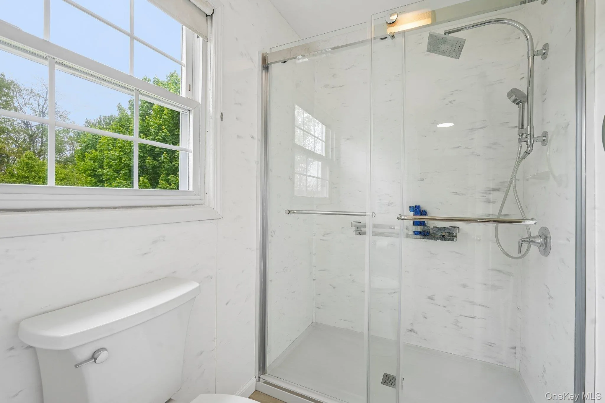 Updated primary bathroom featuring a walk-in glass shower, bright finishes, and natural light. Updated primary bathroom featuring a walk-in glass shower, bright finishes, and natural light.