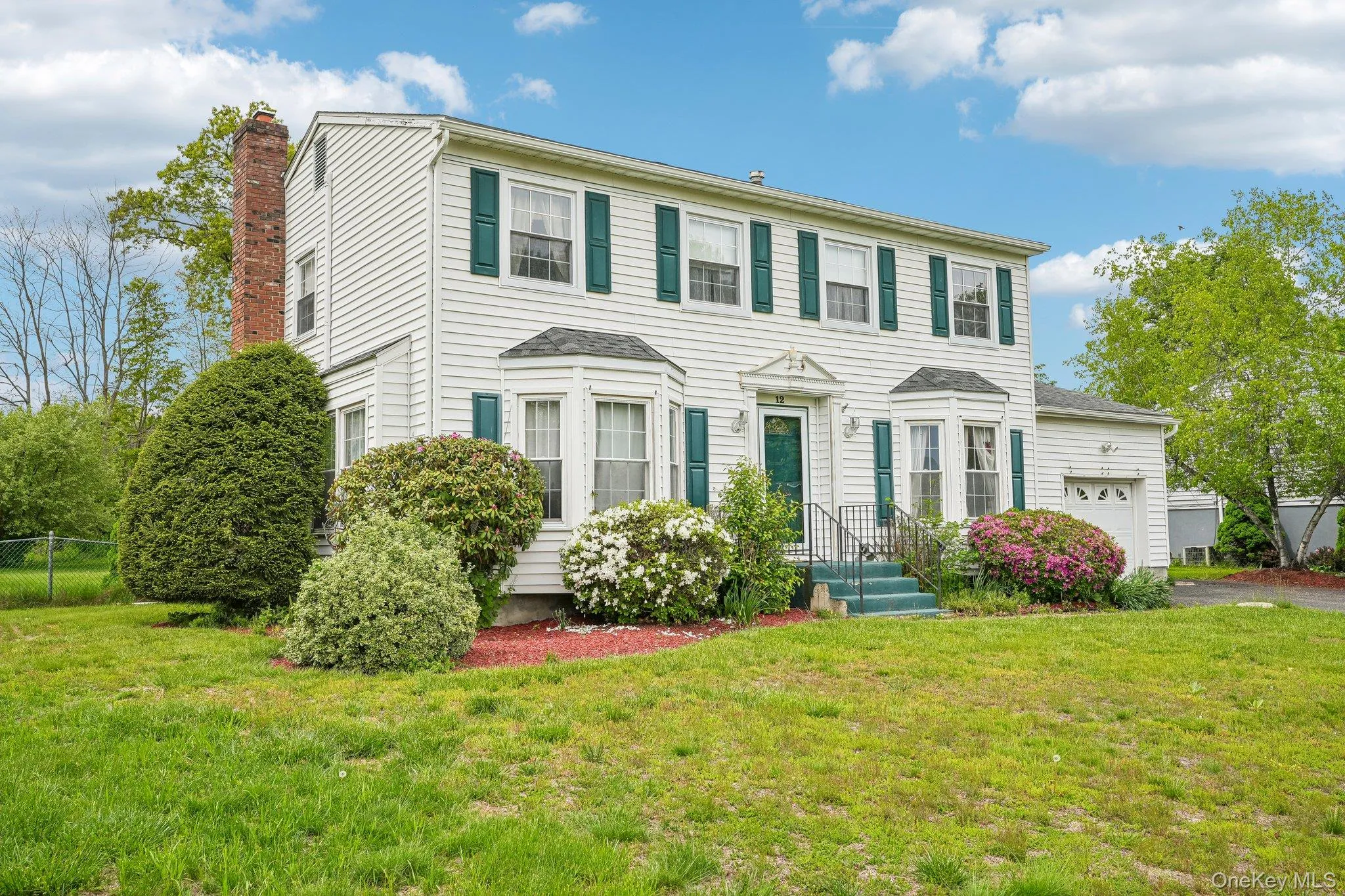 Classic Colonial-style home featuring a spacious front lawn, attached garage, and a beautifully maintained exterior set on a tree-lined property. Classic Colonial-style home featuring a spacious front lawn, attached garage, and a beautifully maintained exterior set on a tree-lined property.