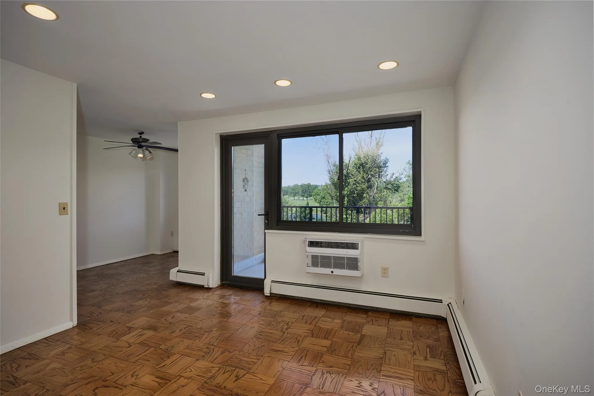 Another view of the Living Room featuring wood parquet flooring, recessed ceiling lighting, with a window and door to balcony Another view of the Living Room featuring wood parquet flooring, recessed ceiling lighting, with a window and door to balcony