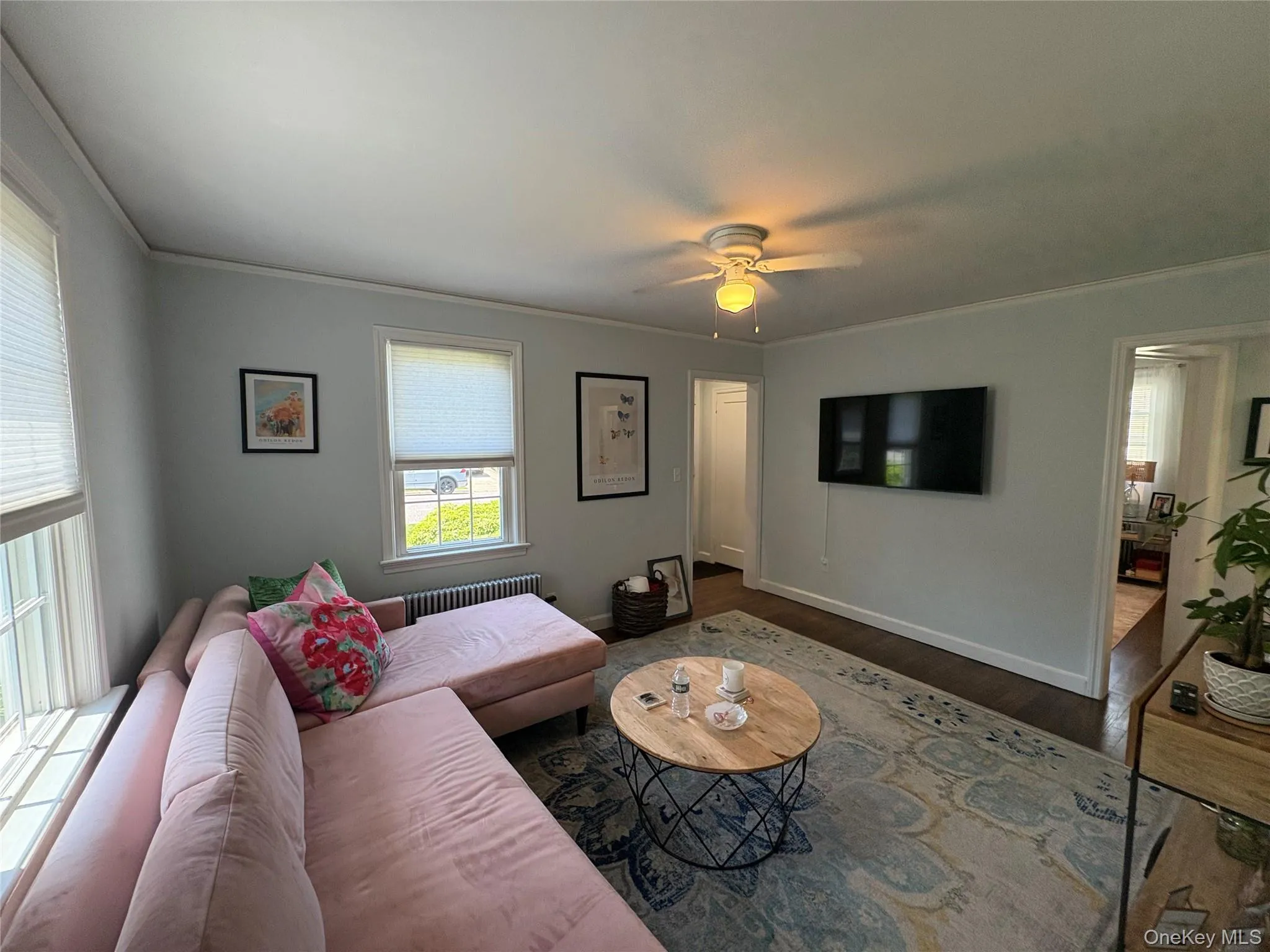 Living area featuring wood finished floors, a ceiling fan, &crown molding Living area featuring wood finished floors, a ceiling fan, &crown molding