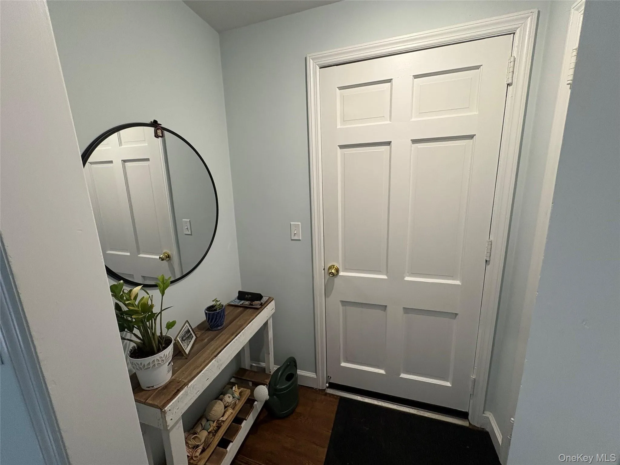 Doorway to outside featuring dark wood-type flooring and baseboards Doorway to outside featuring dark wood-type flooring and baseboards