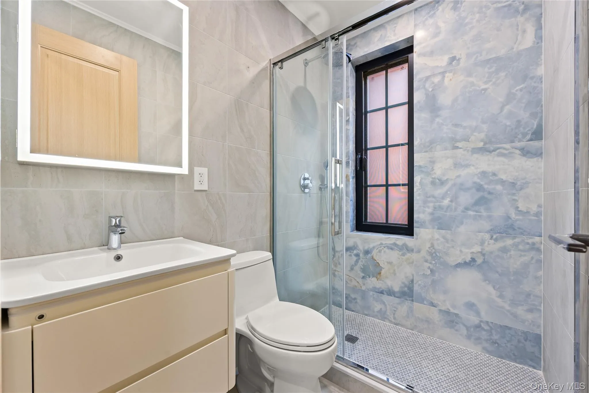 Bathroom with tile walls, vanity, and a shower stall Bathroom with tile walls, vanity, and a shower stall