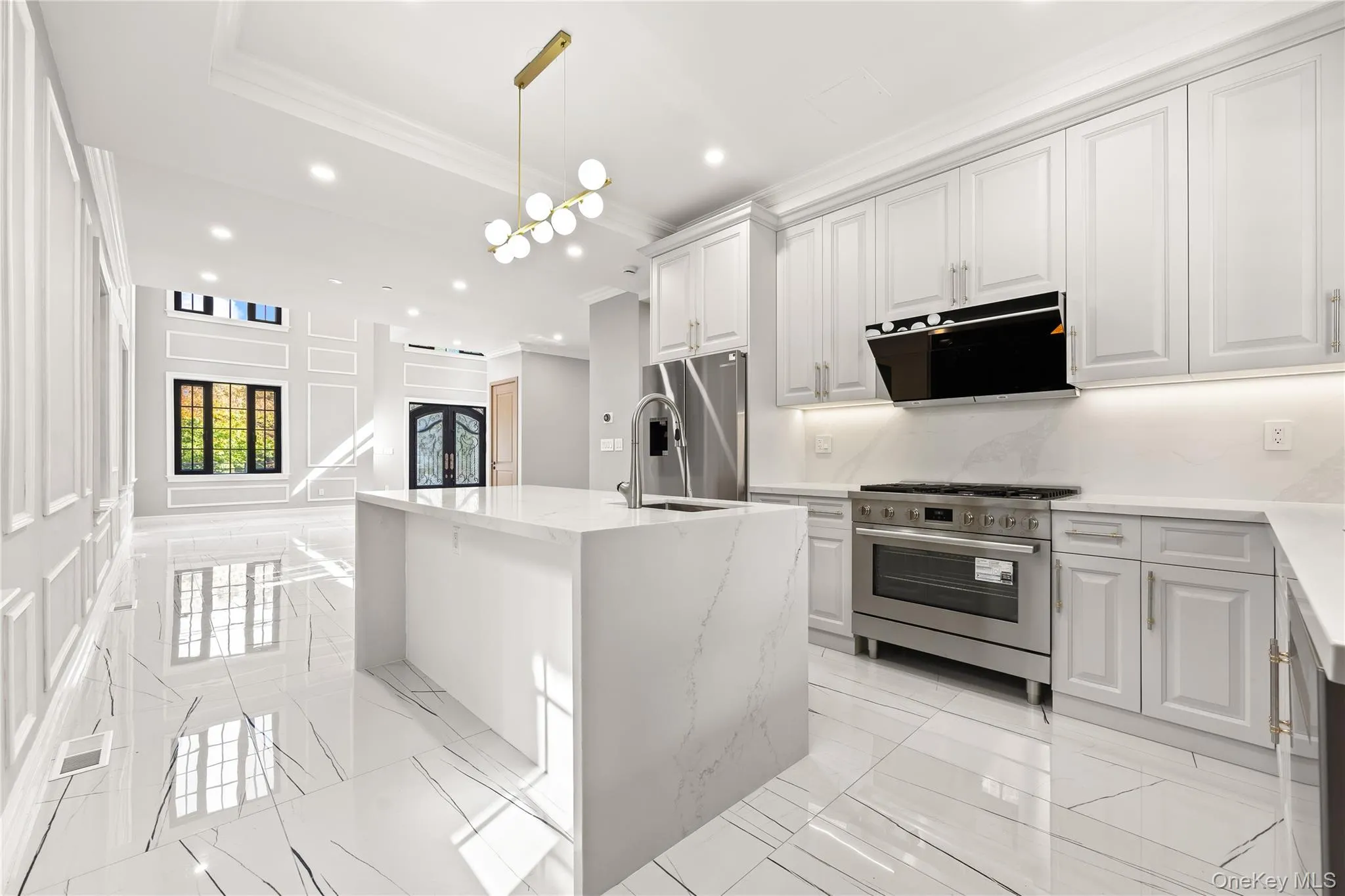Kitchen with a center island with sink, recessed lighting, range hood, appliances with stainless steel finishes, and light stone counters Kitchen with a center island with sink, recessed lighting, range hood, appliances with stainless steel finishes, and light stone counters