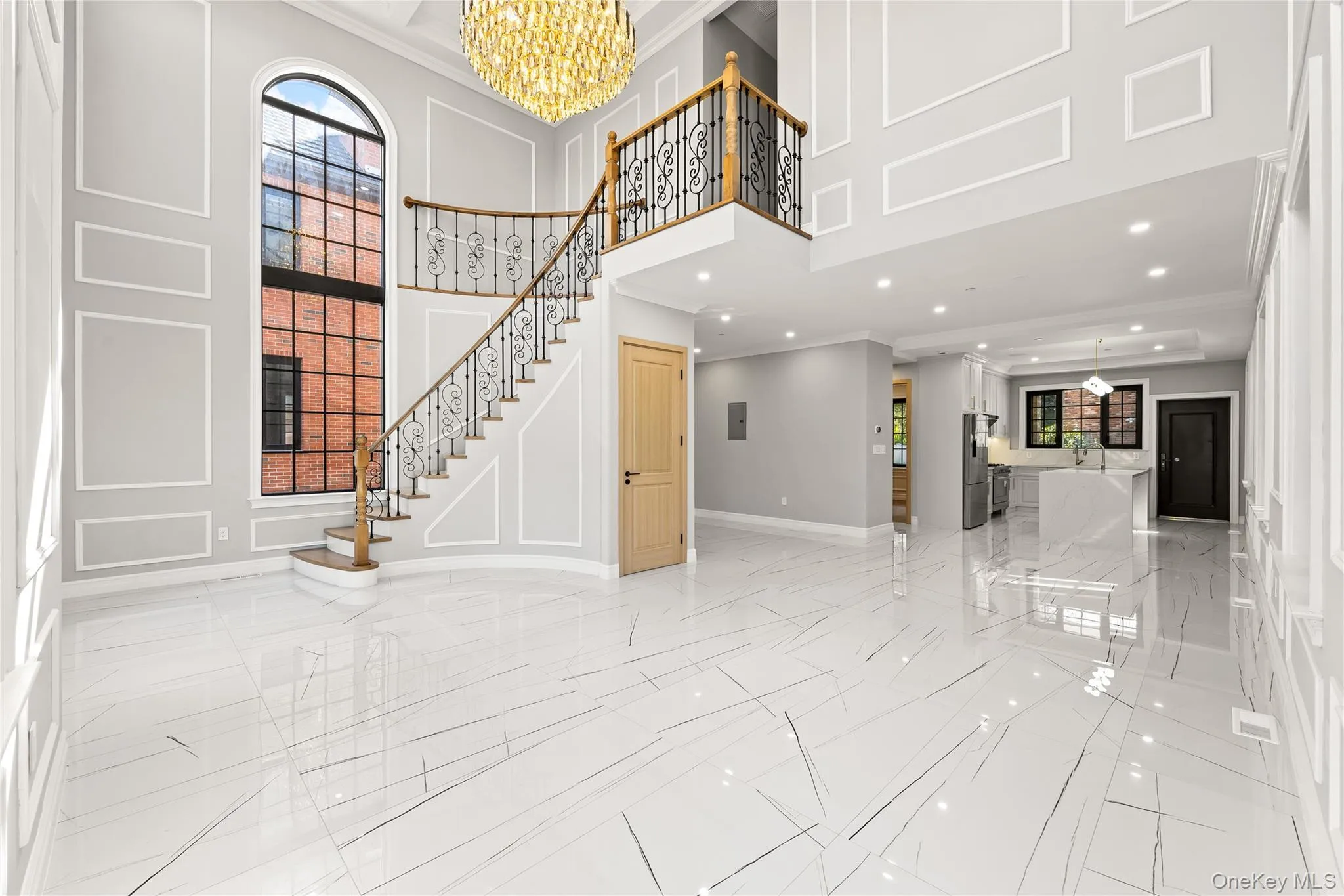 Foyer entrance with a chandelier, ornamental molding, a decorative wall, stairs, and a towering ceiling Foyer entrance with a chandelier, ornamental molding, a decorative wall, stairs, and a towering ceiling