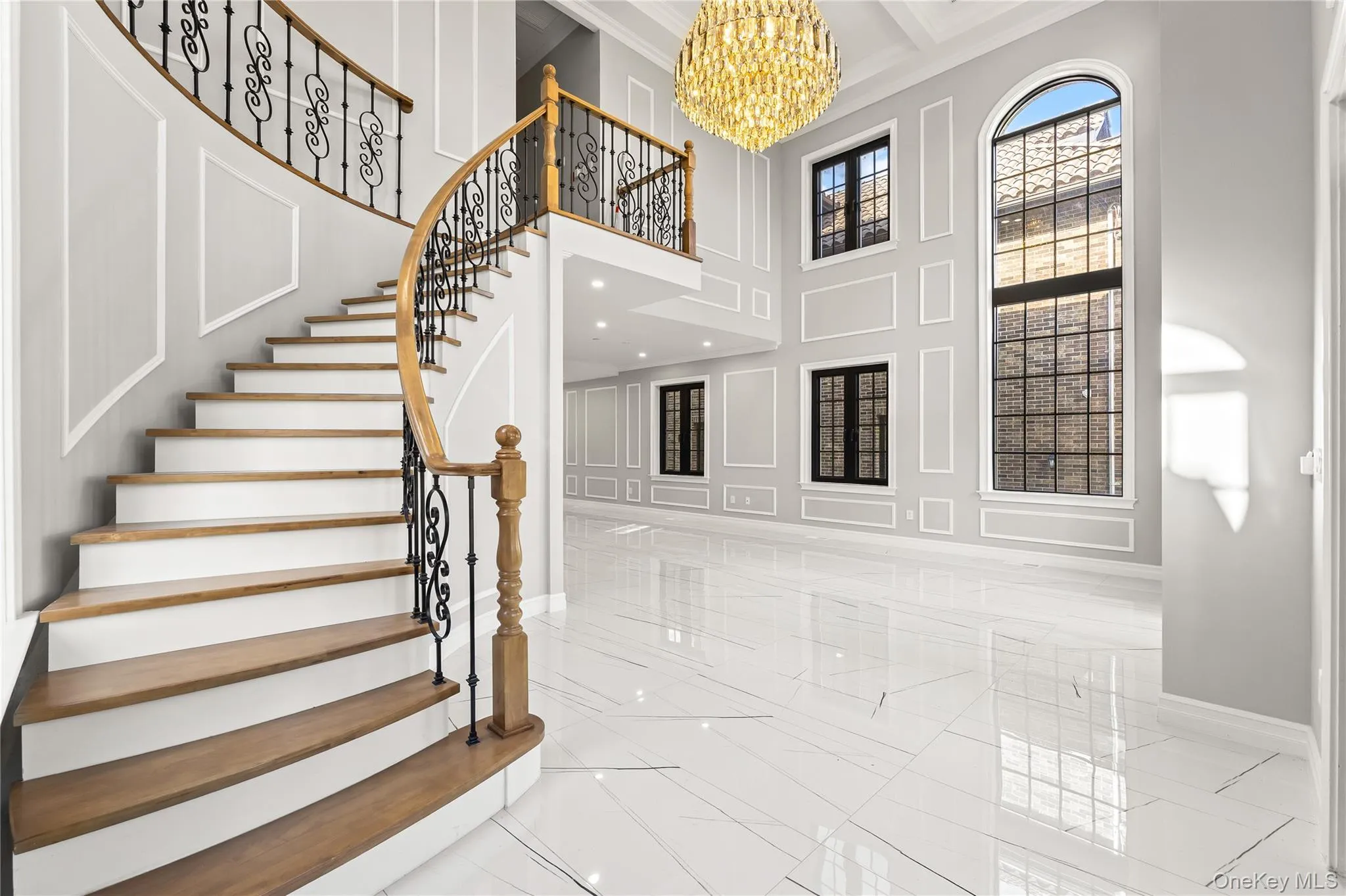 Entrance foyer featuring a decorative wall, a chandelier, a high ceiling, light marble finish floors, and stairs Entrance foyer featuring a decorative wall, a chandelier, a high ceiling, light marble finish floors, and stairs