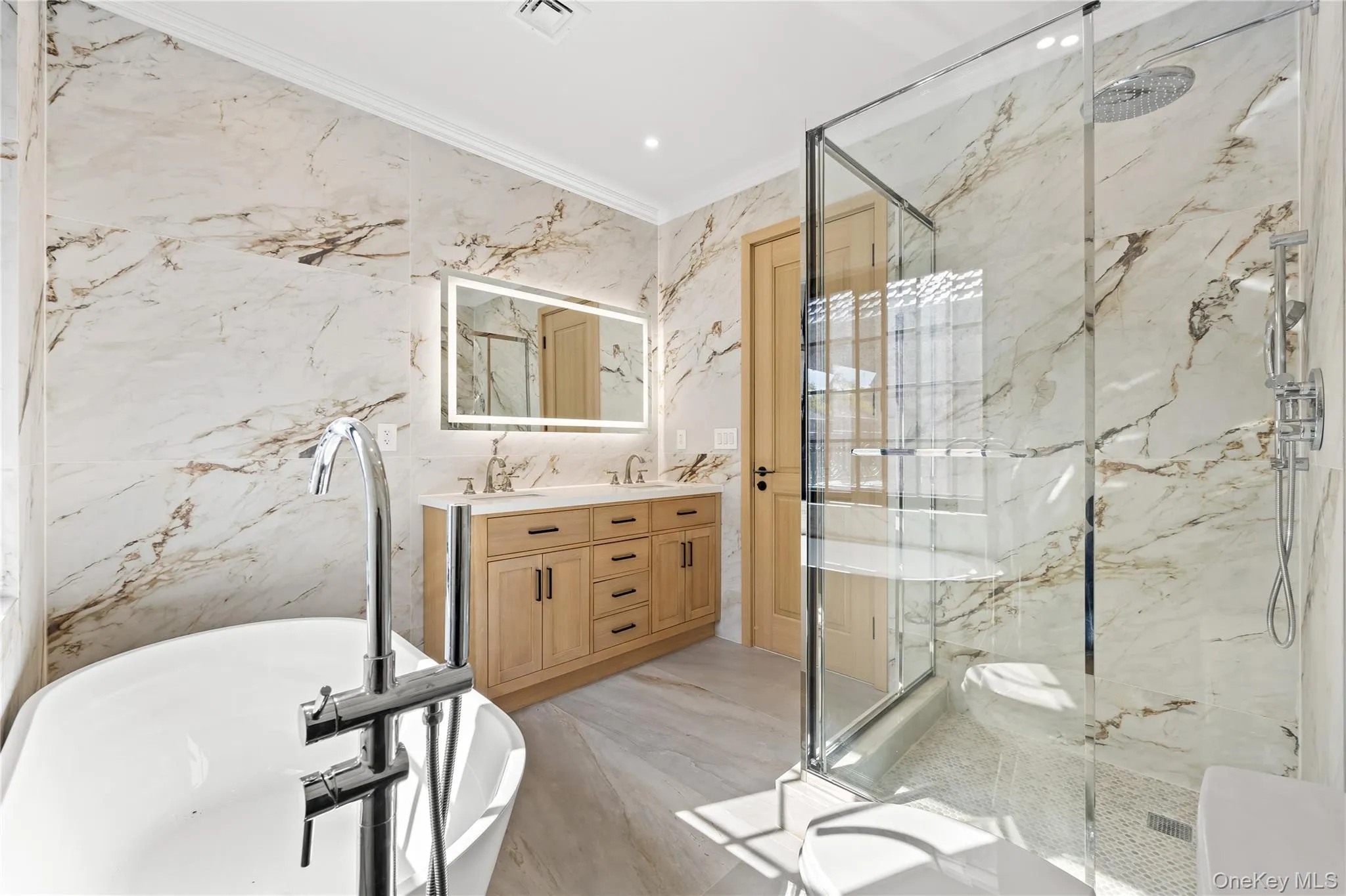 Full bath featuring crown molding, a marble finish shower, a soaking tub, double vanity, and stone wall Full bath featuring crown molding, a marble finish shower, a soaking tub, double vanity, and stone wall