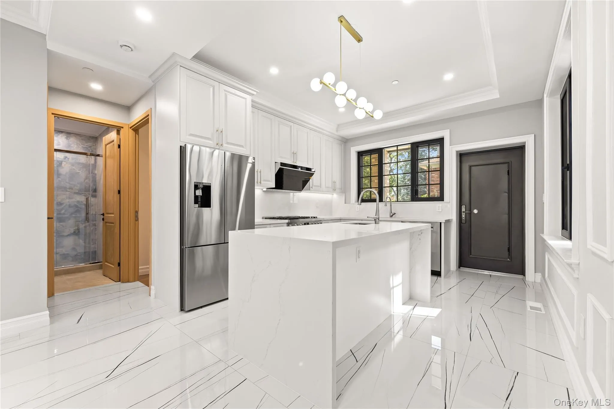 Kitchen featuring white cabinetry, stainless steel fridge, light stone countertops, a center island, and light marble finish flooring Kitchen featuring white cabinetry, stainless steel fridge, light stone countertops, a center island, and light marble finish flooring