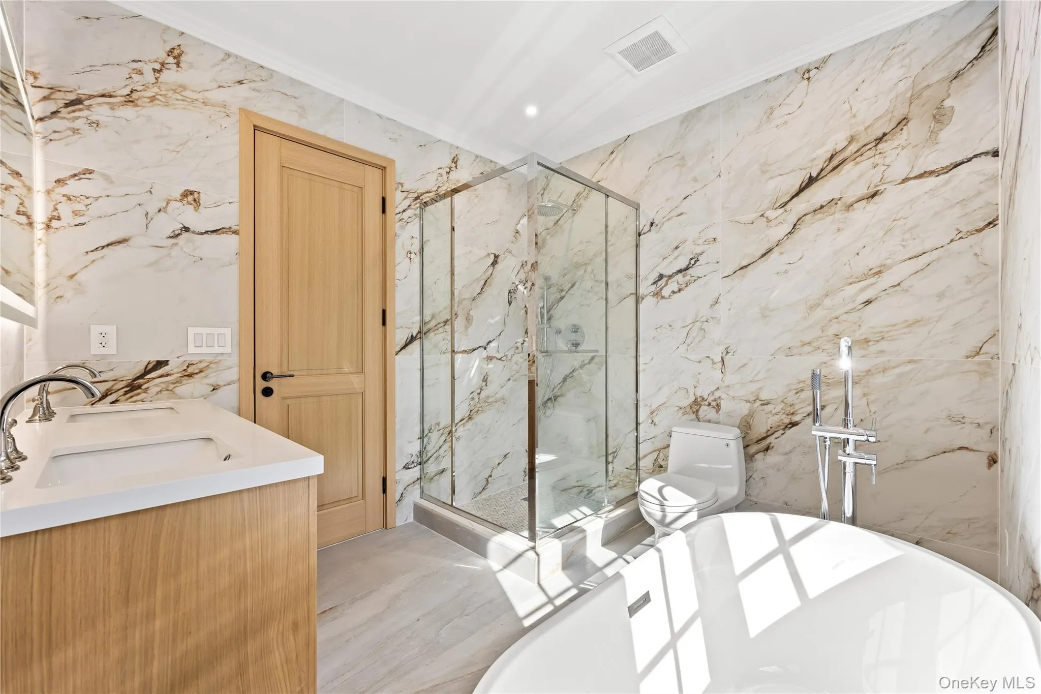Bathroom with stone wall, a freestanding tub, a marble finish shower, double vanity, and recessed lighting Bathroom with stone wall, a freestanding tub, a marble finish shower, double vanity, and recessed lighting