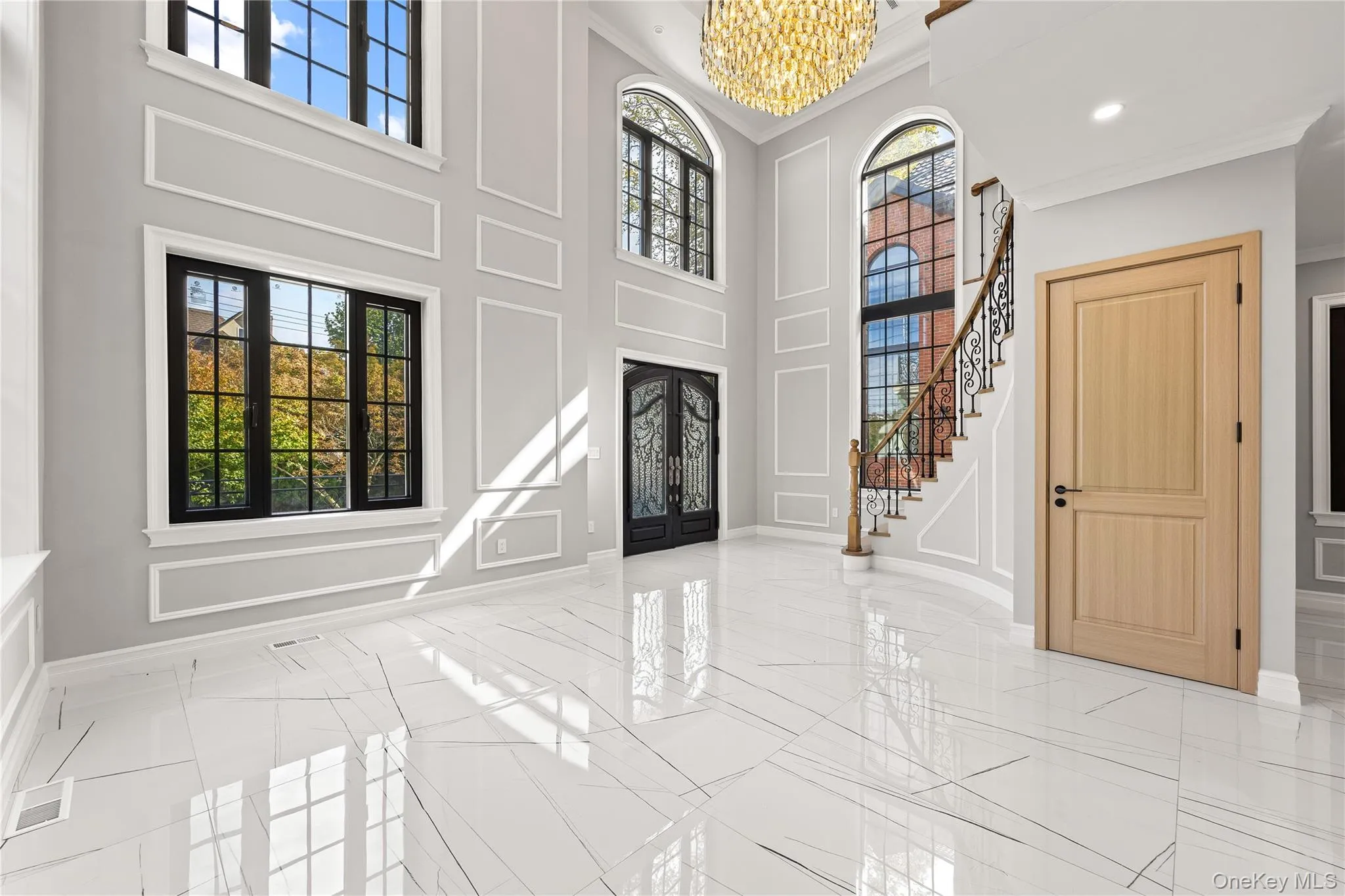 Entrance foyer featuring a chandelier, healthy amount of natural light, stairway, a high ceiling, and crown molding Entrance foyer featuring a chandelier, healthy amount of natural light, stairway, a high ceiling, and crown molding