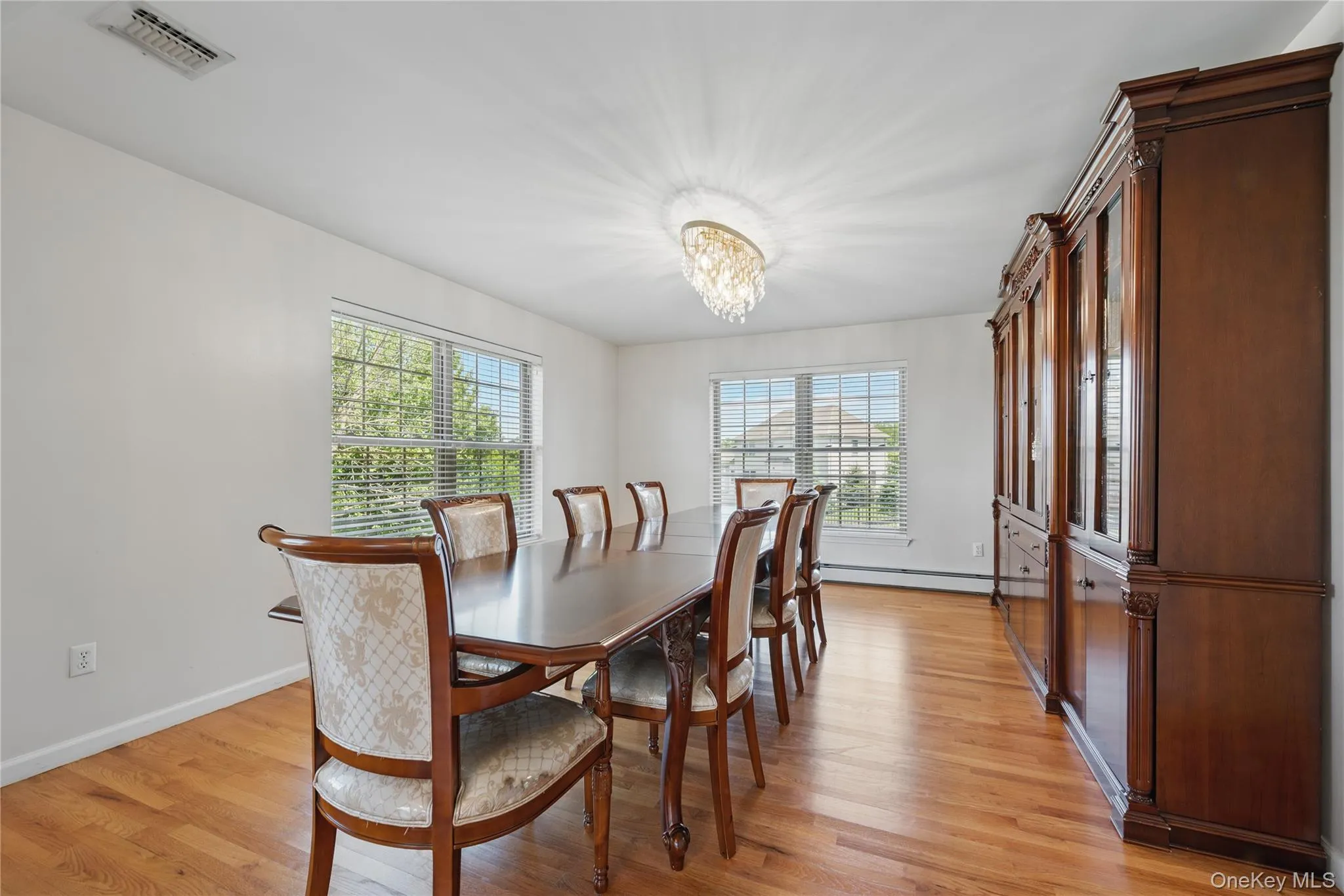 Dining area with light wood finished floors, baseboards, a chandelier, and a baseboard heating unit Dining area with light wood finished floors, baseboards, a chandelier, and a baseboard heating unit