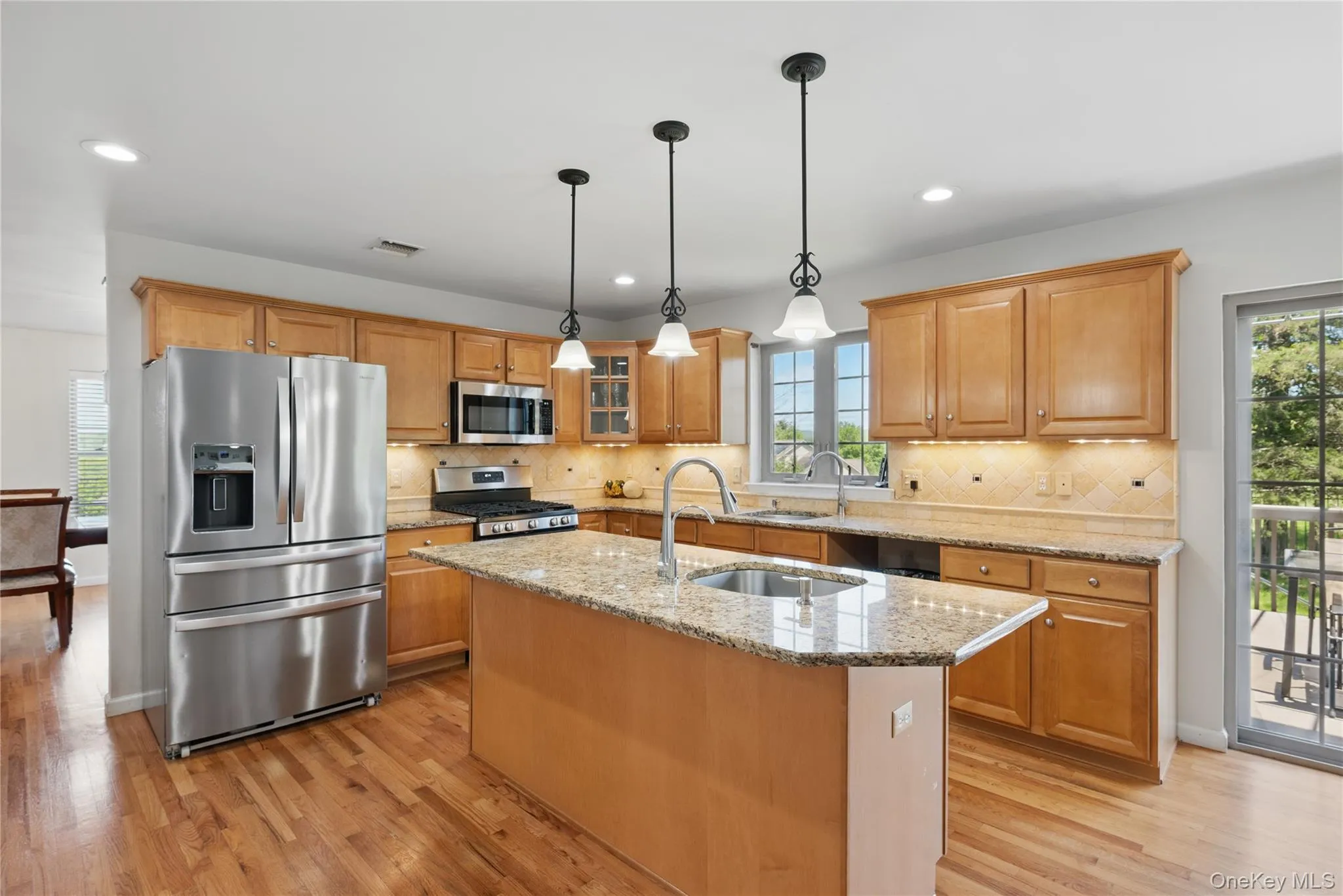 Kitchen featuring appliances with stainless steel finishes, light wood finished floors, a sink, recessed lighting, and a center island with sink Kitchen featuring appliances with stainless steel finishes, light wood finished floors, a sink, recessed lighting, and a center island with sink