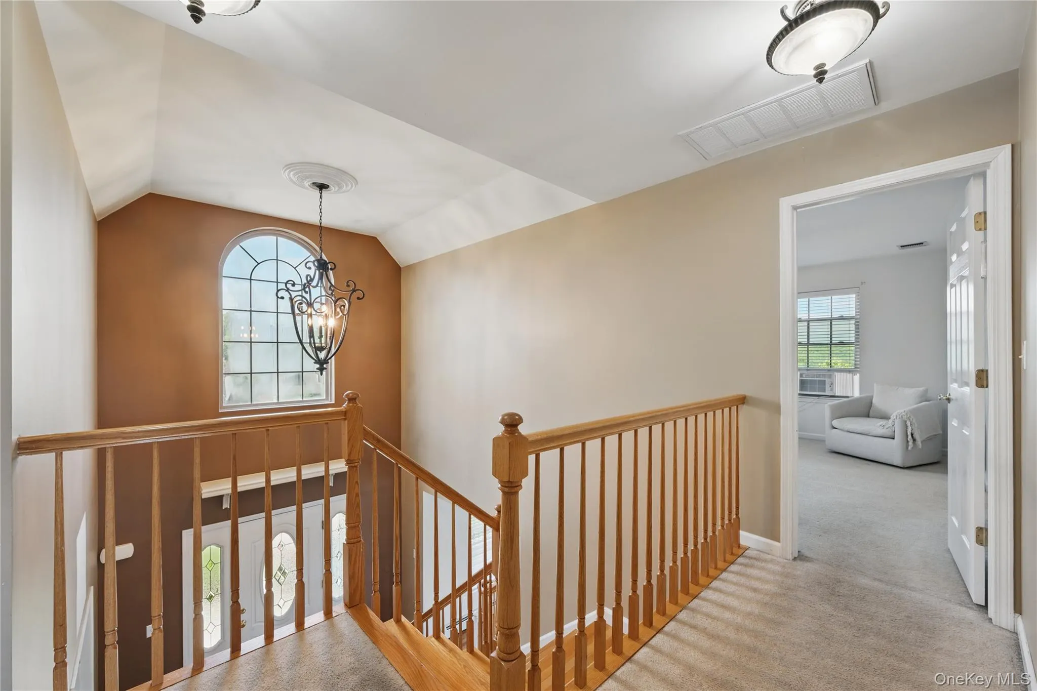 Hall featuring an upstairs landing, a chandelier, vaulted ceiling, and carpet flooring Hall featuring an upstairs landing, a chandelier, vaulted ceiling, and carpet flooring