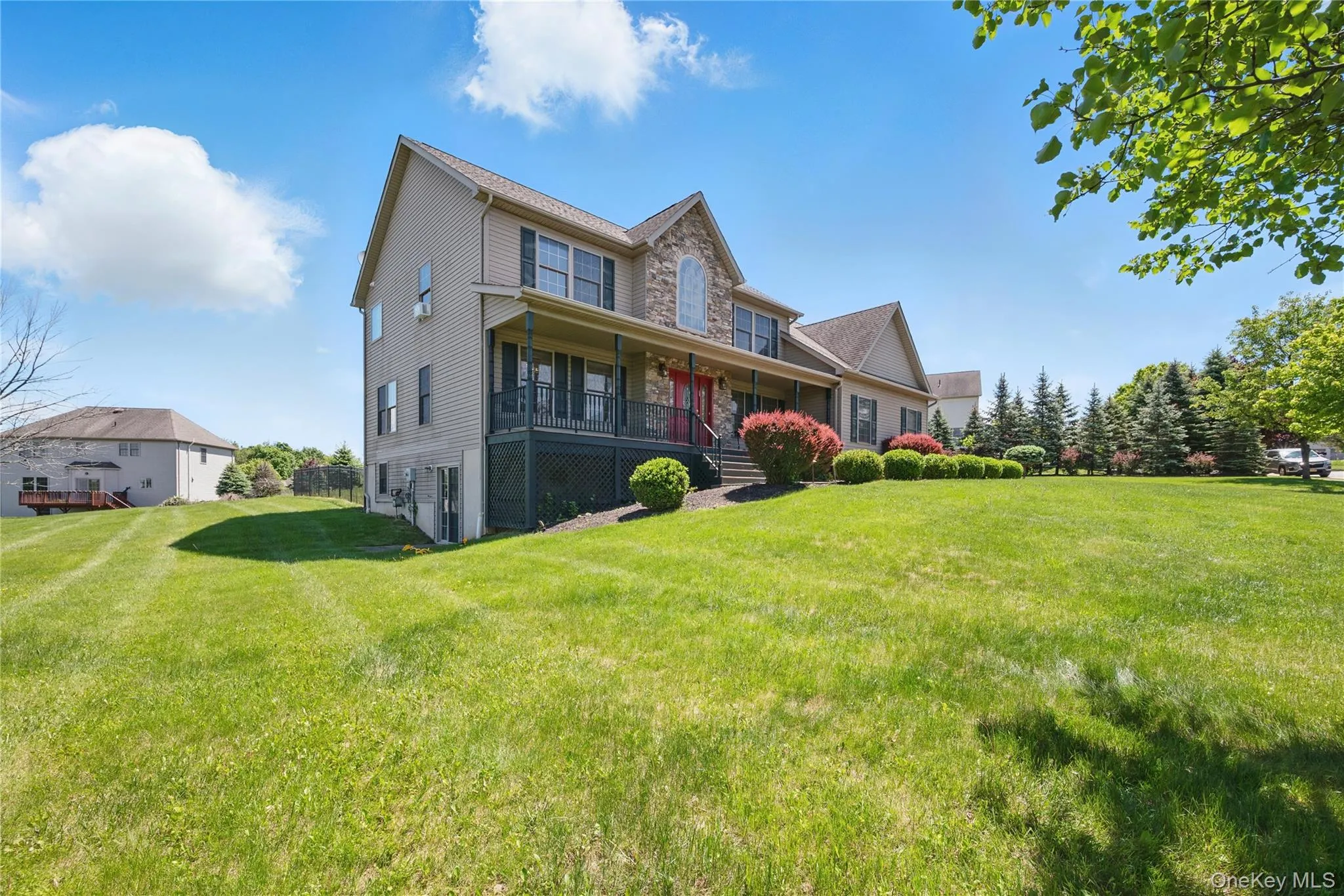 Rear view of property featuring a porch, a lawn, and stone siding Rear view of property featuring a porch, a lawn, and stone siding