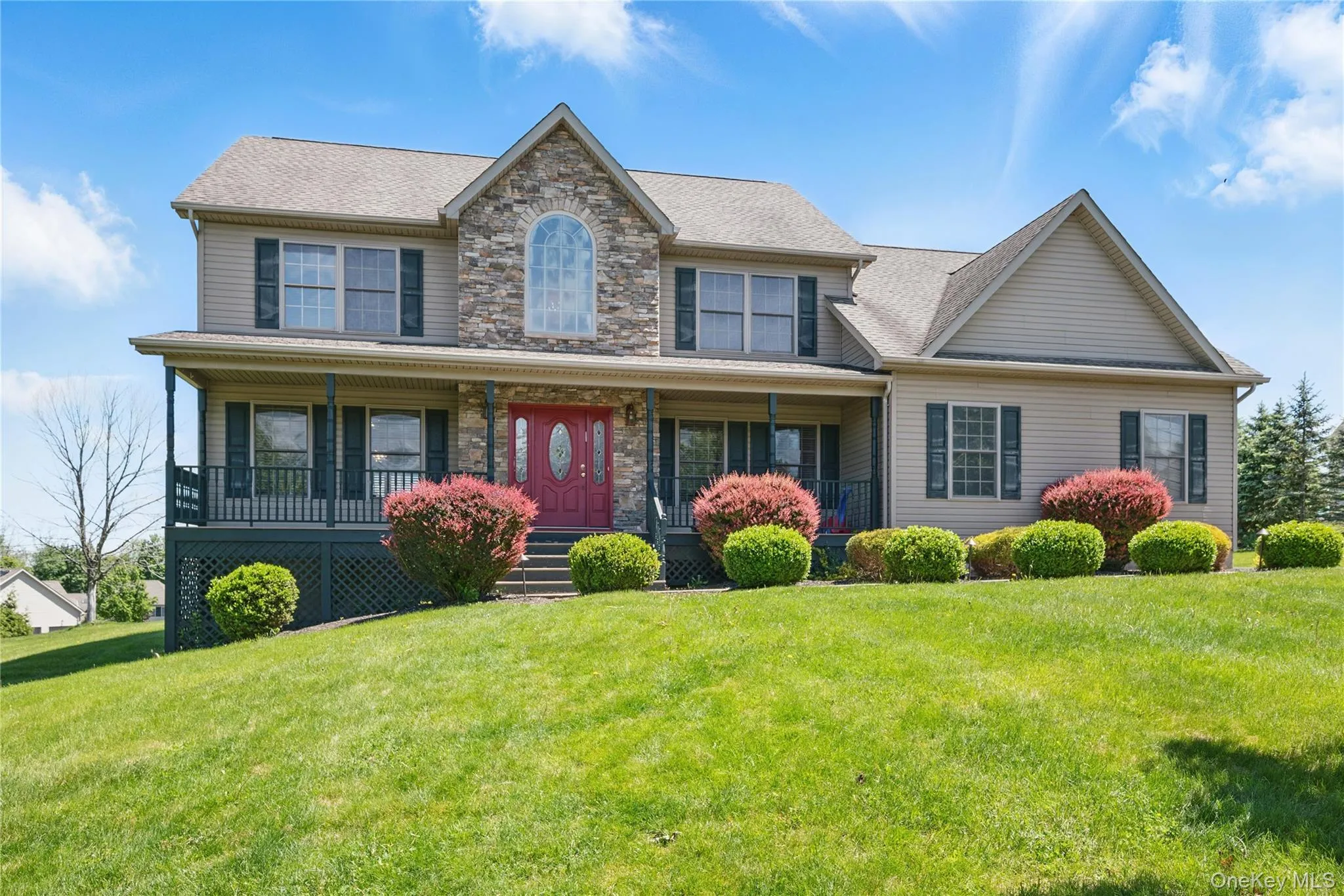 View of front of home with a porch, a front yard, and stone siding View of front of home with a porch, a front yard, and stone siding