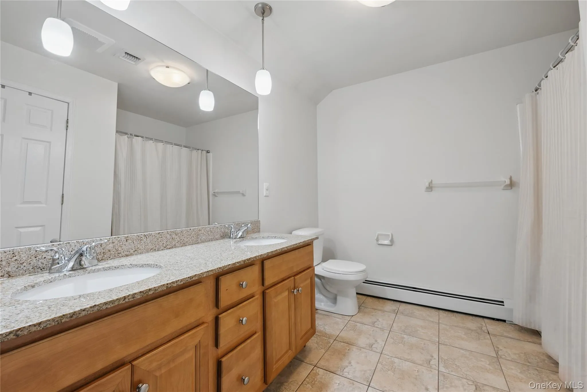 Full bathroom with baseboard heating, double vanity, toilet, and tile patterned flooring Full bathroom with baseboard heating, double vanity, toilet, and tile patterned flooring