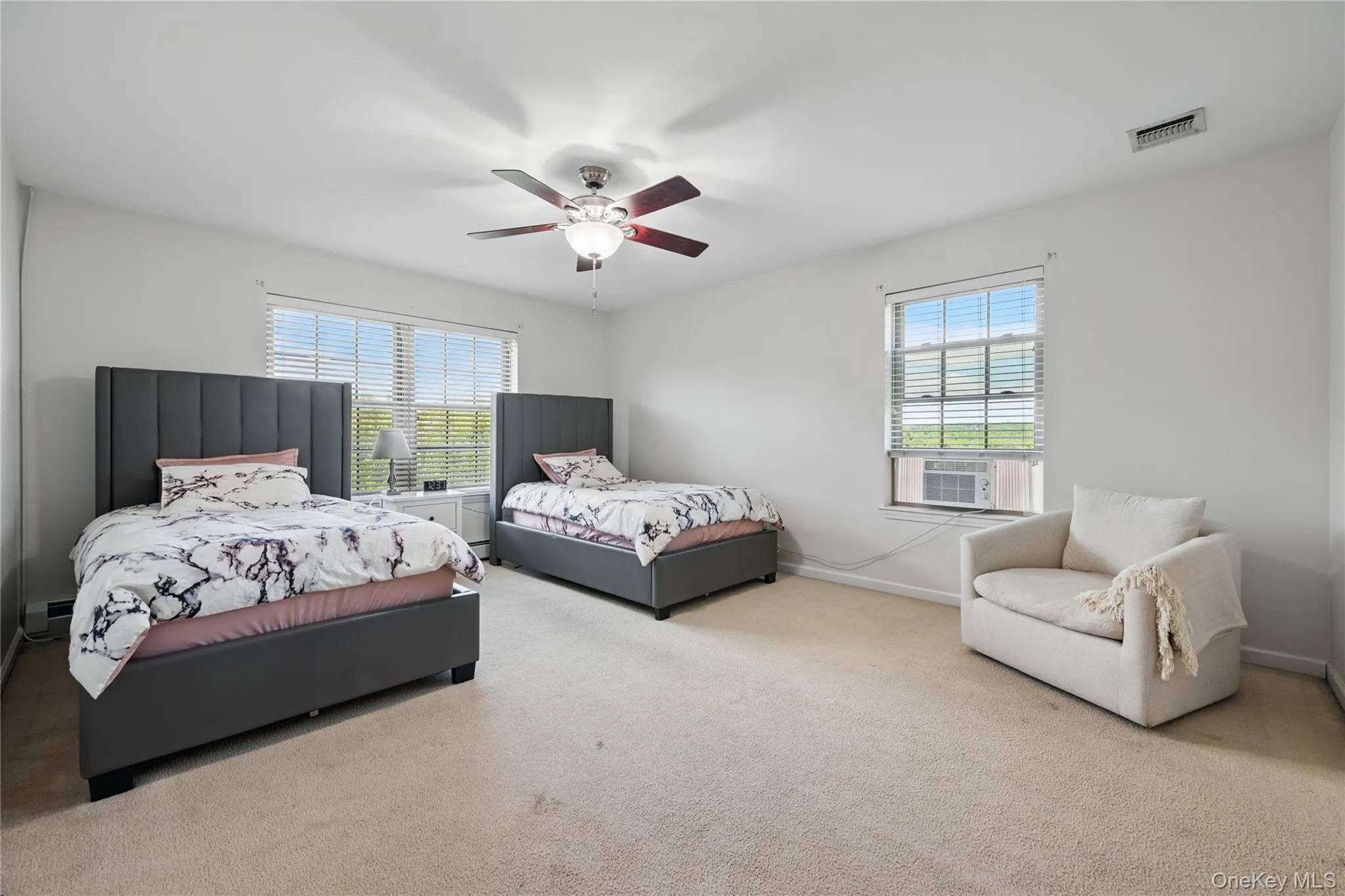 Bedroom featuring multiple windows, carpet, and baseboards Bedroom featuring multiple windows, carpet, and baseboards