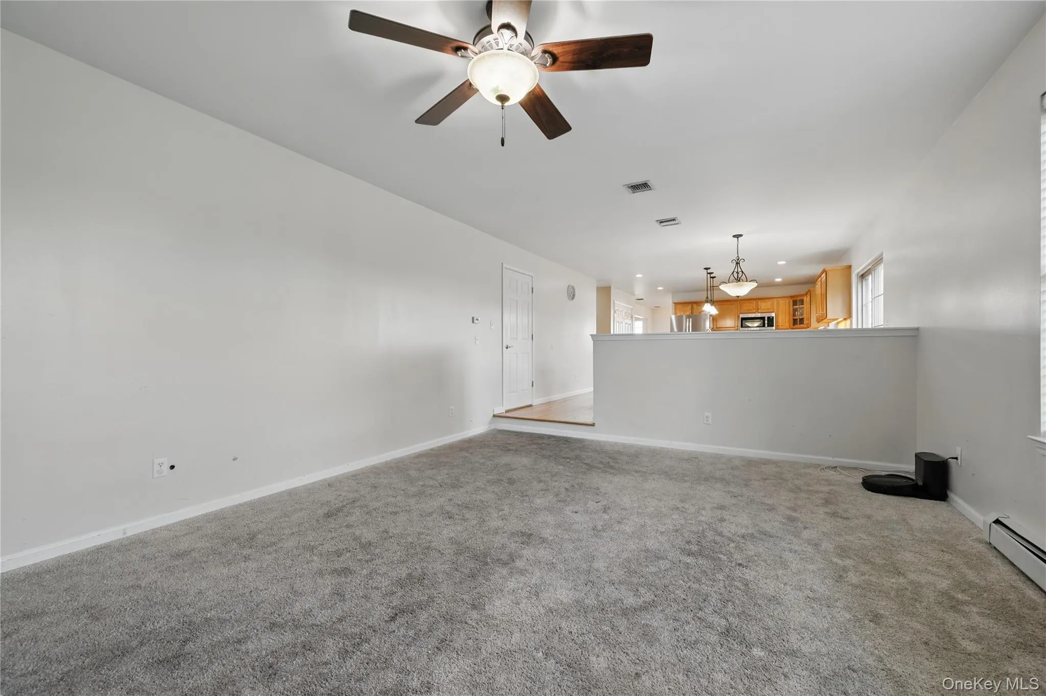Unfurnished living room with carpet, ceiling fan, recessed lighting, baseboards, and a baseboard radiator Unfurnished living room with carpet, ceiling fan, recessed lighting, baseboards, and a baseboard radiator