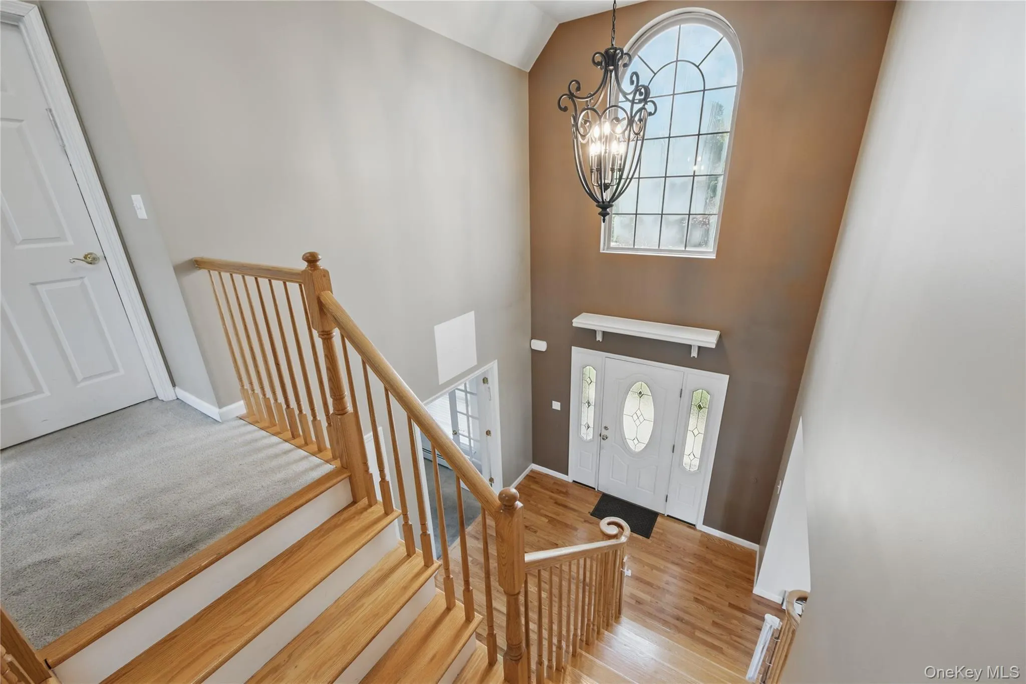Entrance foyer featuring a chandelier, healthy amount of natural light, high vaulted ceiling, wood finished floors, and baseboards Entrance foyer featuring a chandelier, healthy amount of natural light, high vaulted ceiling, wood finished floors, and baseboards