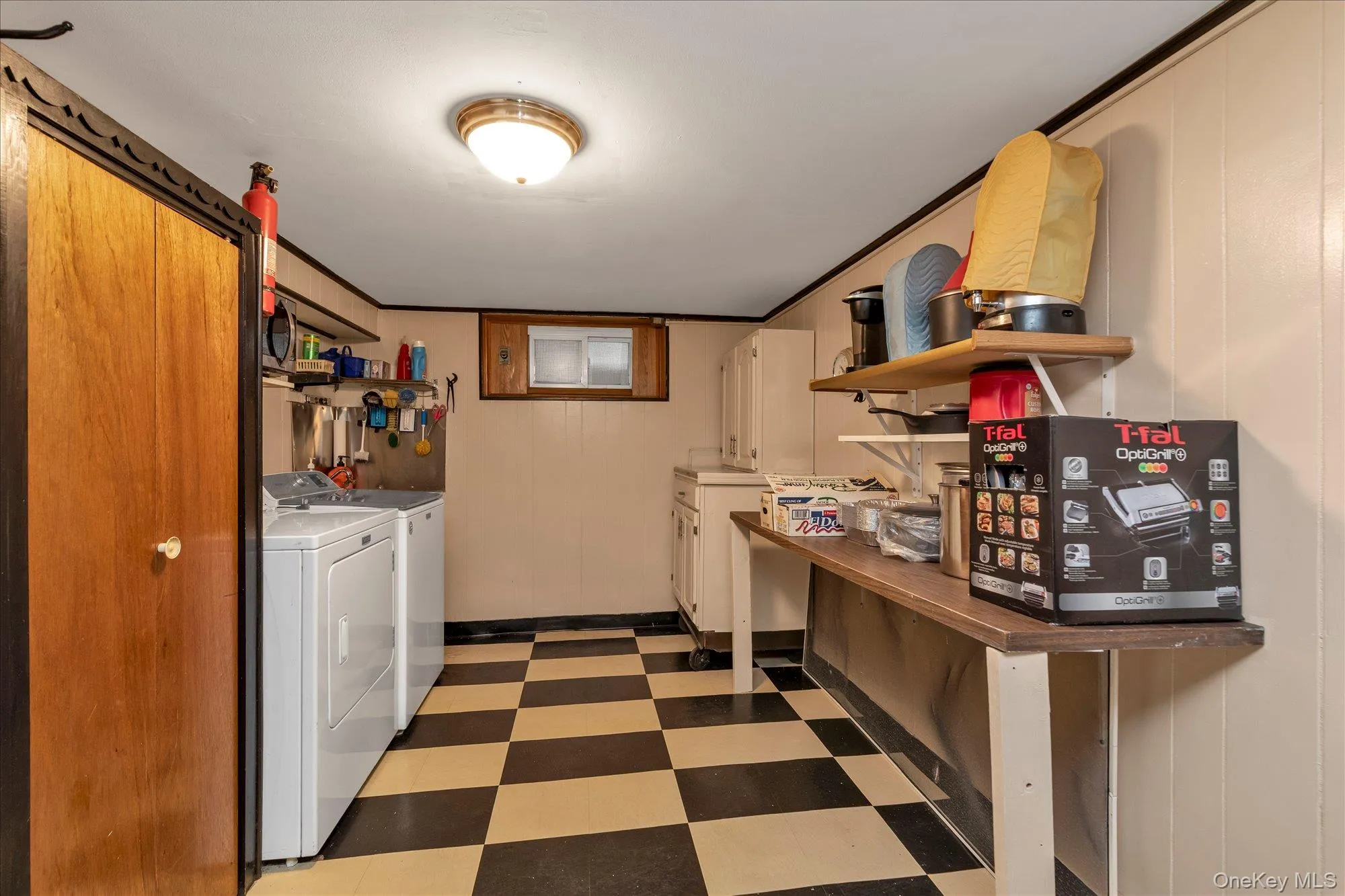 Utility area featuring a checkered floor, beadboard walls, and a built-in countertop with shelving Utility area featuring a checkered floor, beadboard walls, and a built-in countertop with shelving