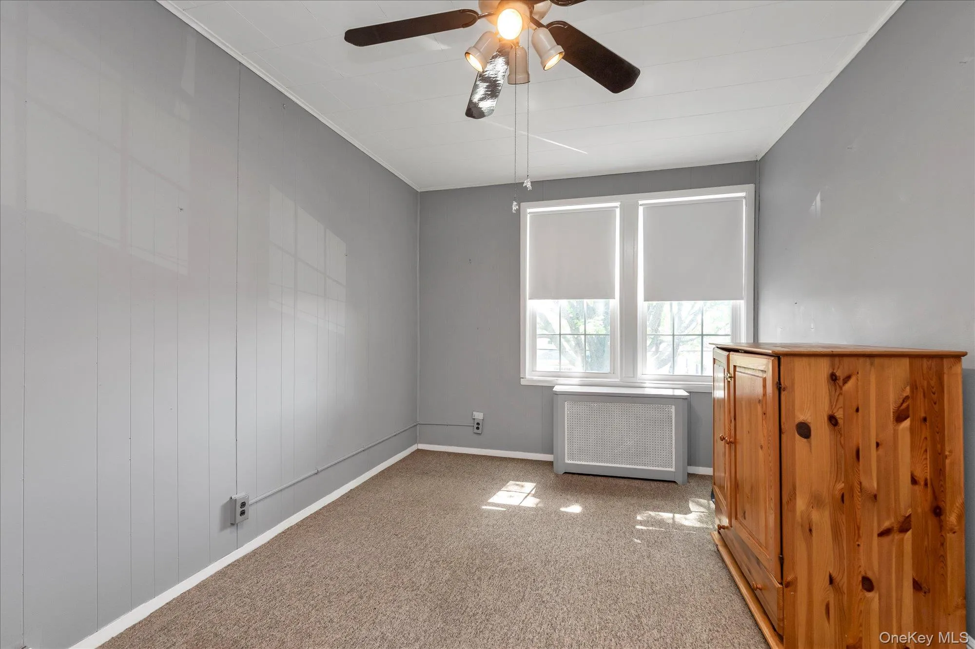 Room featuring neutral gray walls and ceiling, brown carpeting, and a ceiling fan with light fixture Room featuring neutral gray walls and ceiling, brown carpeting, and a ceiling fan with light fixture
