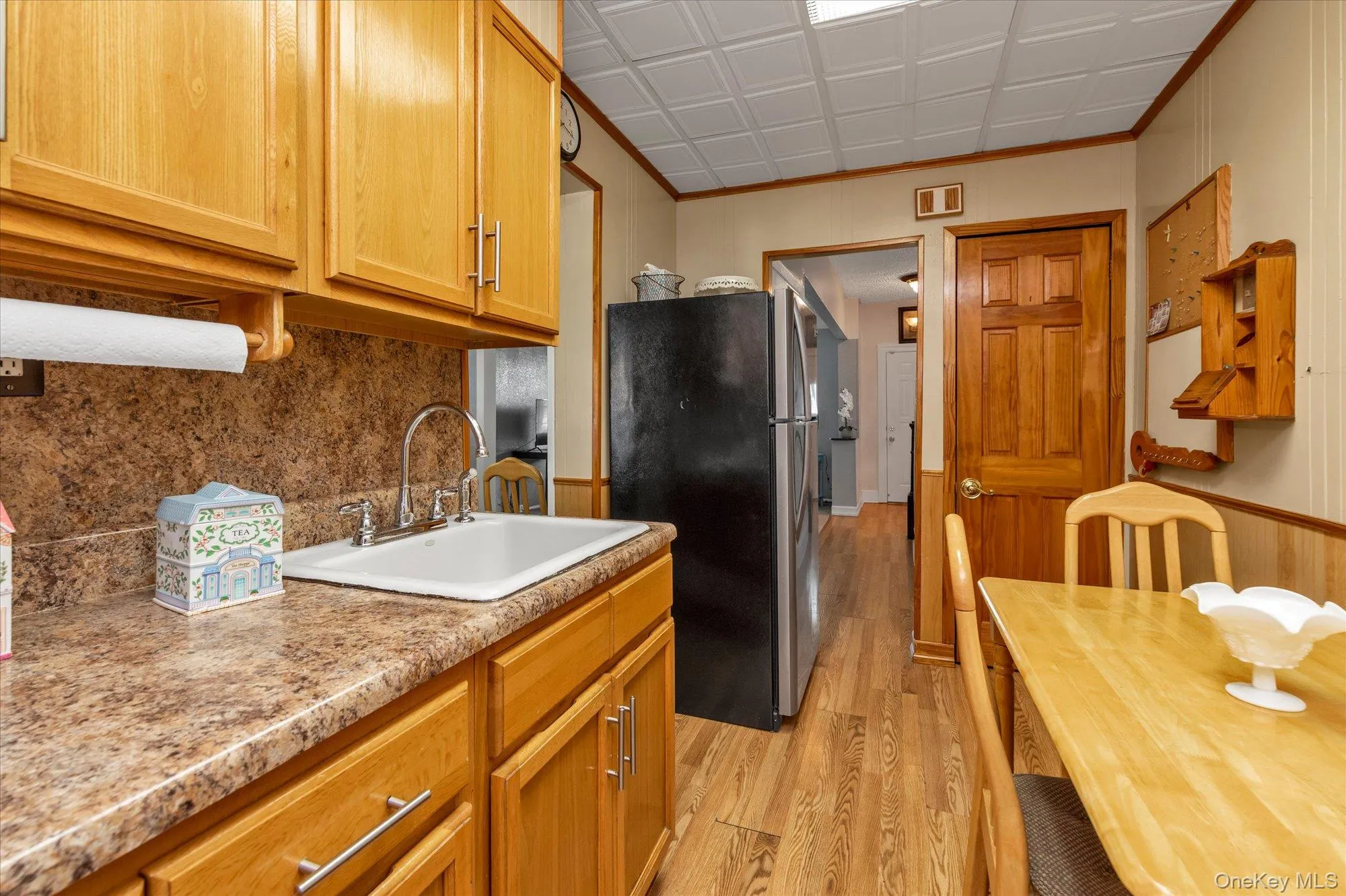 Kitchen featuring wood-finish cabinetry, a white drop-in sink with a gooseneck faucet, and mottled-finish countertops Kitchen featuring wood-finish cabinetry, a white drop-in sink with a gooseneck faucet, and mottled-finish countertops