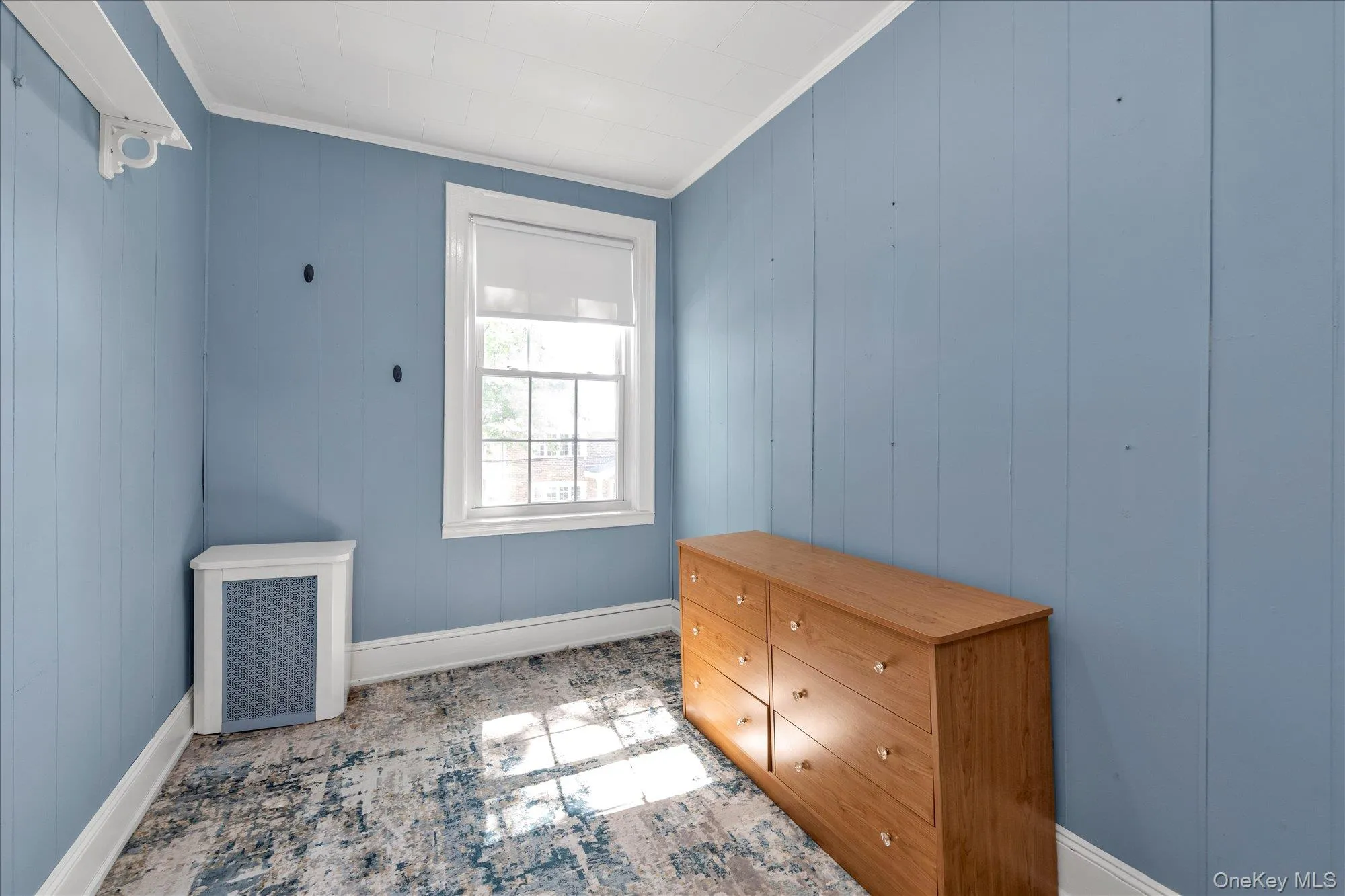 Interior space featuring vertical plank wall paneling, a single casement window with white trim, and white baseboards Interior space featuring vertical plank wall paneling, a single casement window with white trim, and white baseboards
