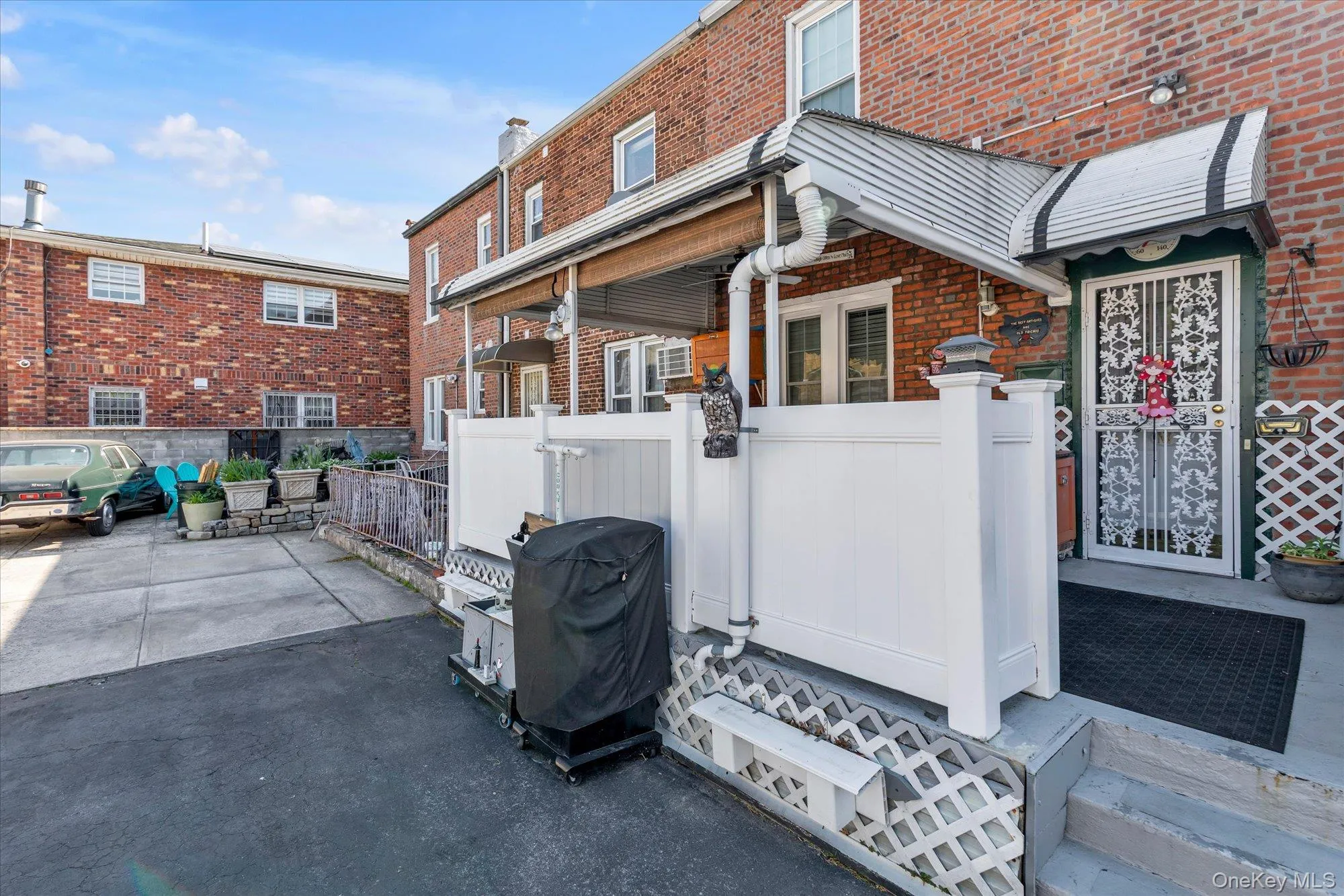 Red brick exterior featuring a white privacy fence and a corrugated metal awning Red brick exterior featuring a white privacy fence and a corrugated metal awning