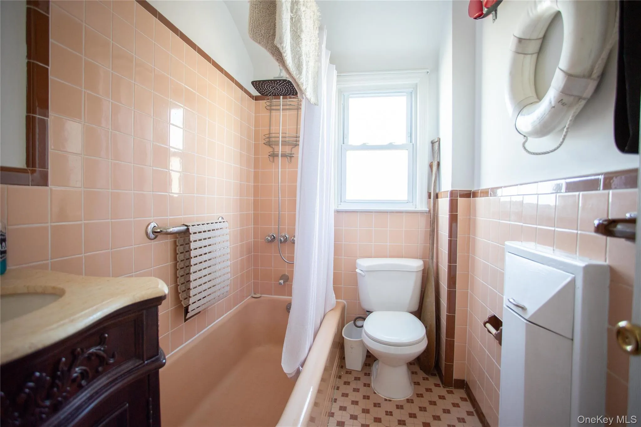 Full bath with shower / tub combo with curtain, tile walls, vanity, and a wainscoted wall Full bath with shower / tub combo with curtain, tile walls, vanity, and a wainscoted wall