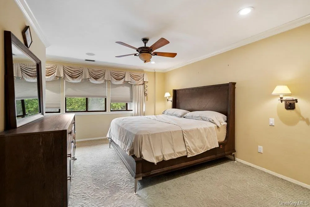 Carpeted room featuring multiple windows with blinds, a ceiling fan, recessed lighting, and wall sconces Carpeted room featuring multiple windows with blinds, a ceiling fan, recessed lighting, and wall sconces
