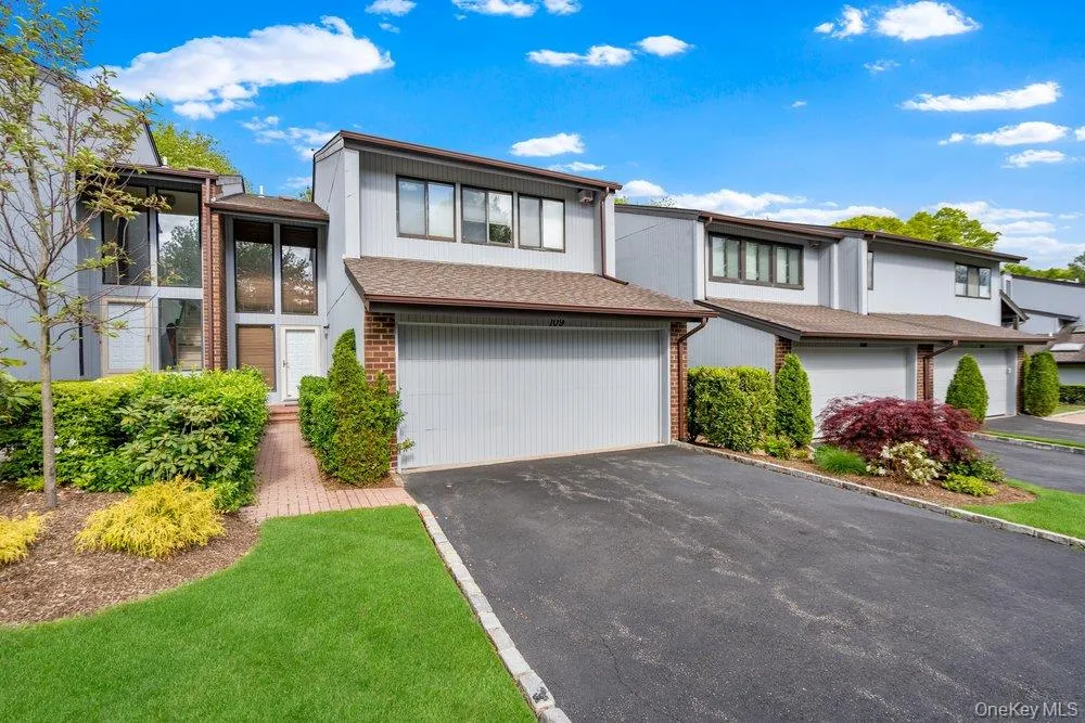 Contemporary residence featuring a light gray exterior with brick accents and a dark brown roofline Contemporary residence featuring a light gray exterior with brick accents and a dark brown roofline