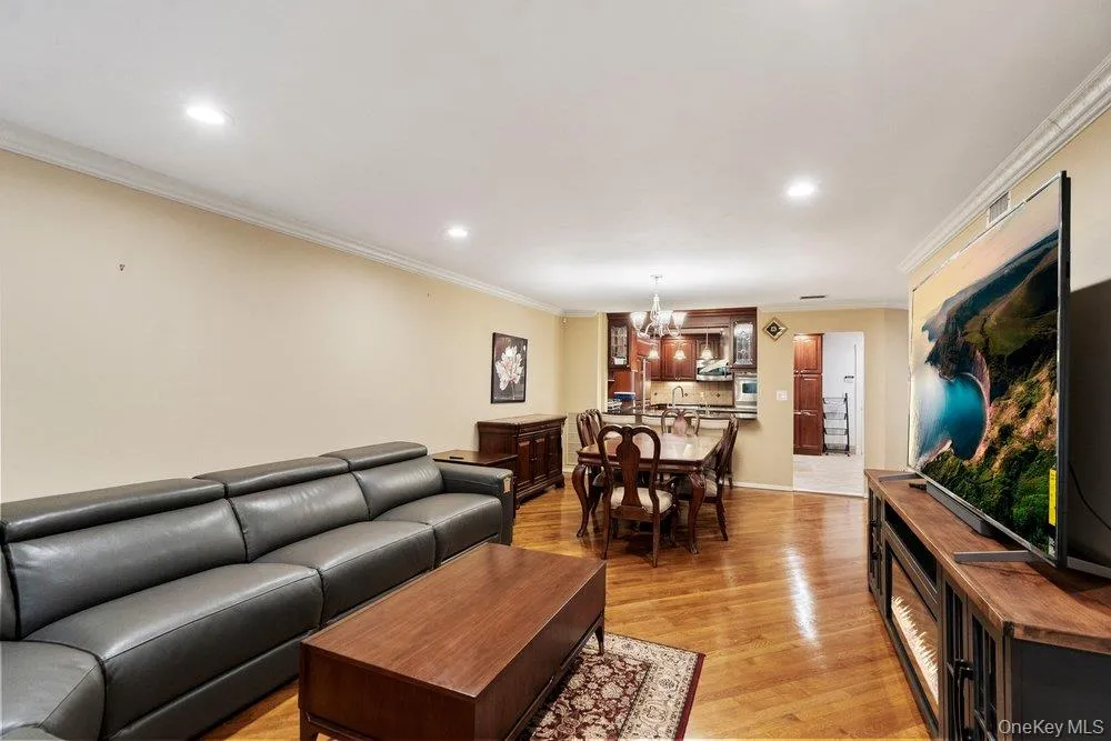 Open-concept living area with wood-finish flooring, recessed lighting, and crown molding Open-concept living area with wood-finish flooring, recessed lighting, and crown molding